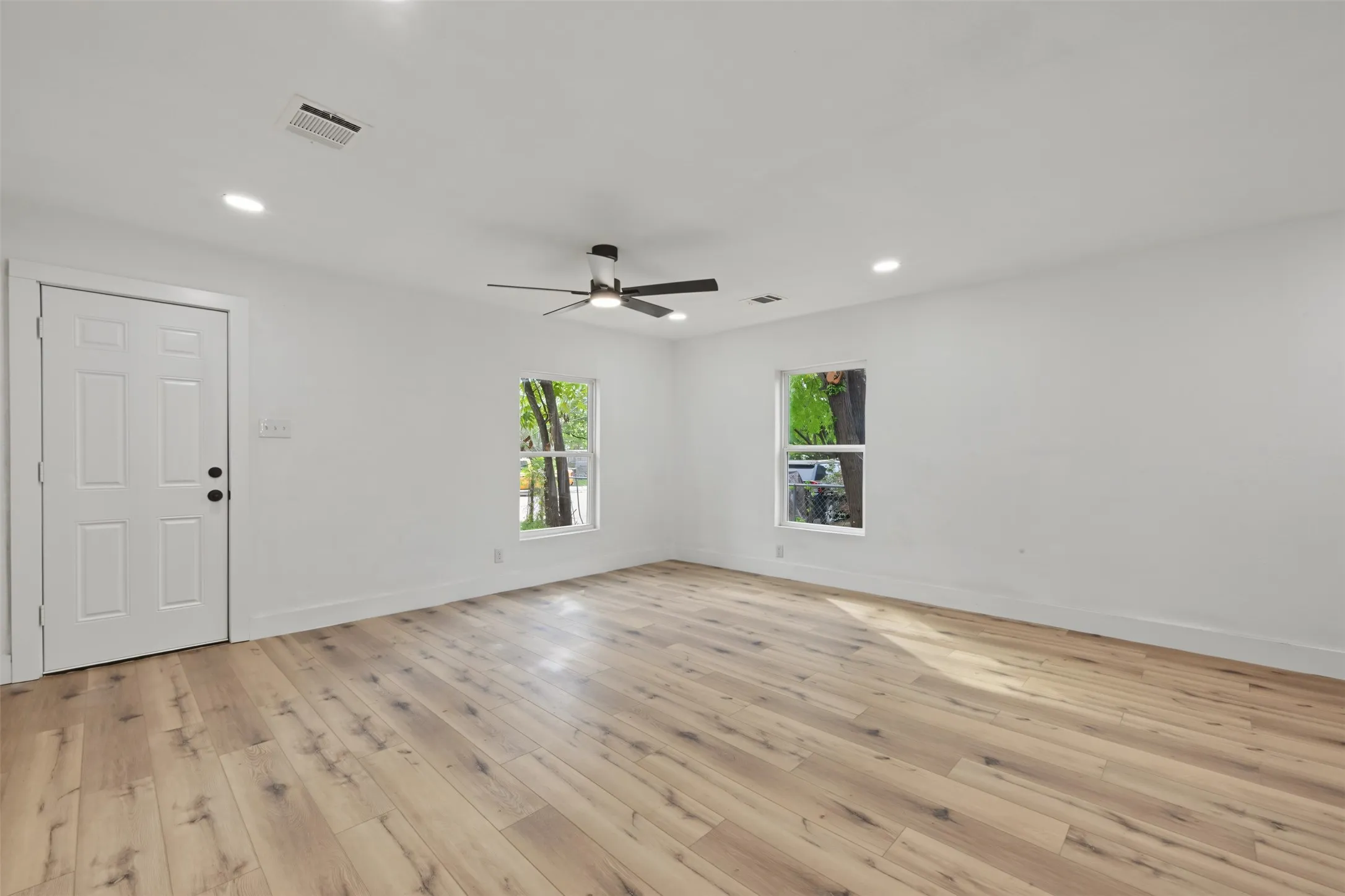 Interior space featuring wood-finish flooring, recessed lighting, a ceiling fan with integrated lighting, and two windows