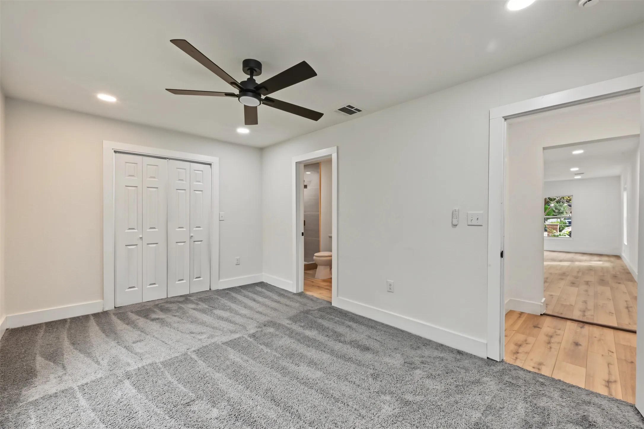 Neutral interior space featuring wall-to-wall carpeting, recessed lighting, a five-blade ceiling fan, and bifold closet doors