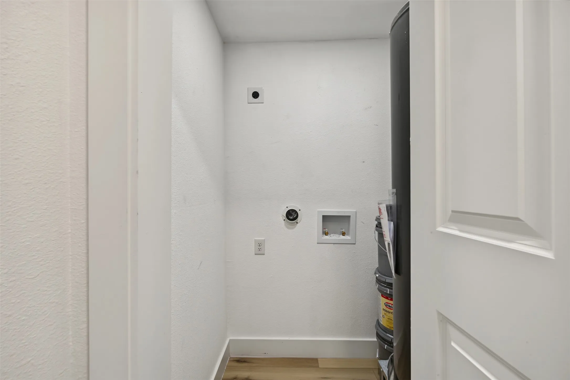 Utility closet featuring wood-finish flooring, dedicated water hookups, and integrated appliance connections