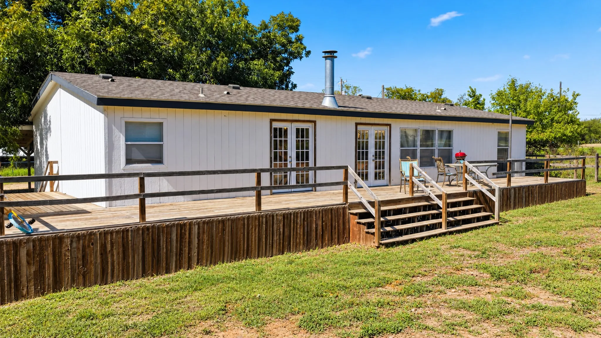 Exterior siding, expansive wood-finished deck, dual glass-paneled entry doors, metal chimney flue, and multi-level wooden staircases