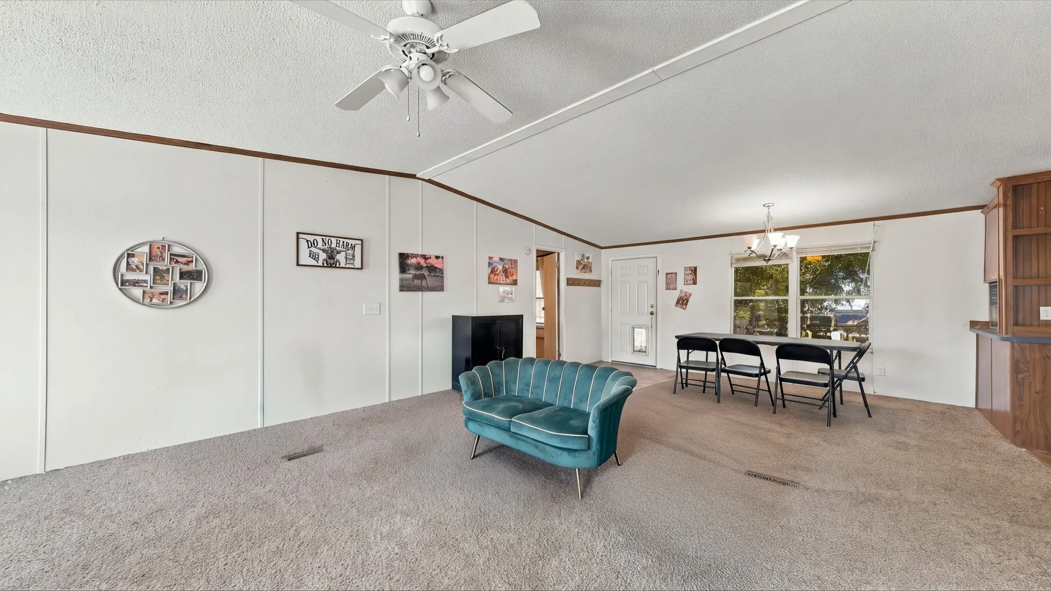 Open-concept interior featuring vaulted ceilings, a ceiling fan with integrated lighting, wall-to-wall carpeting, and wood-finish cabinetry