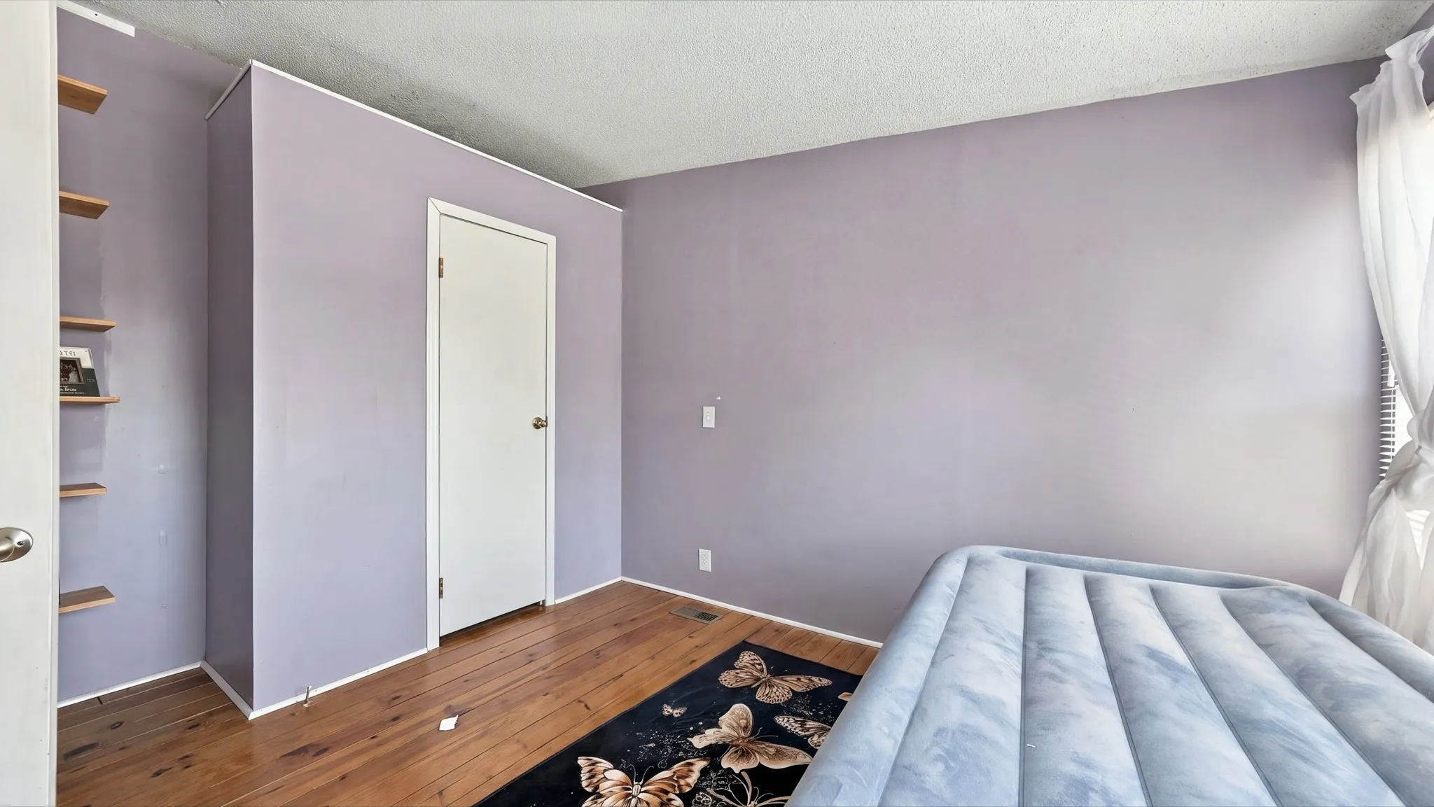 Room featuring wood-finish flooring and built-in wall shelving