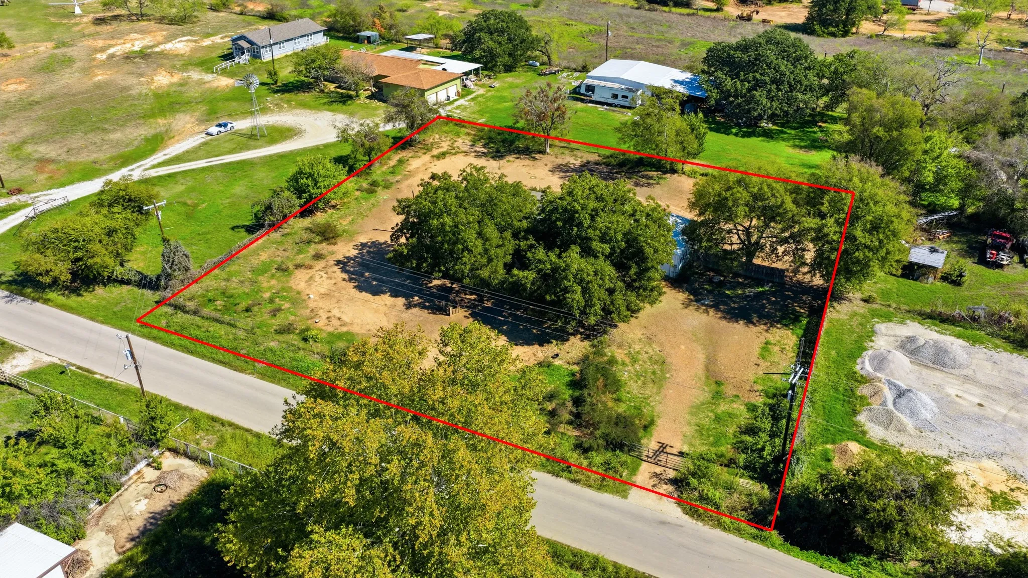 Expansive parcel featuring mature trees, partial fencing, and direct road access