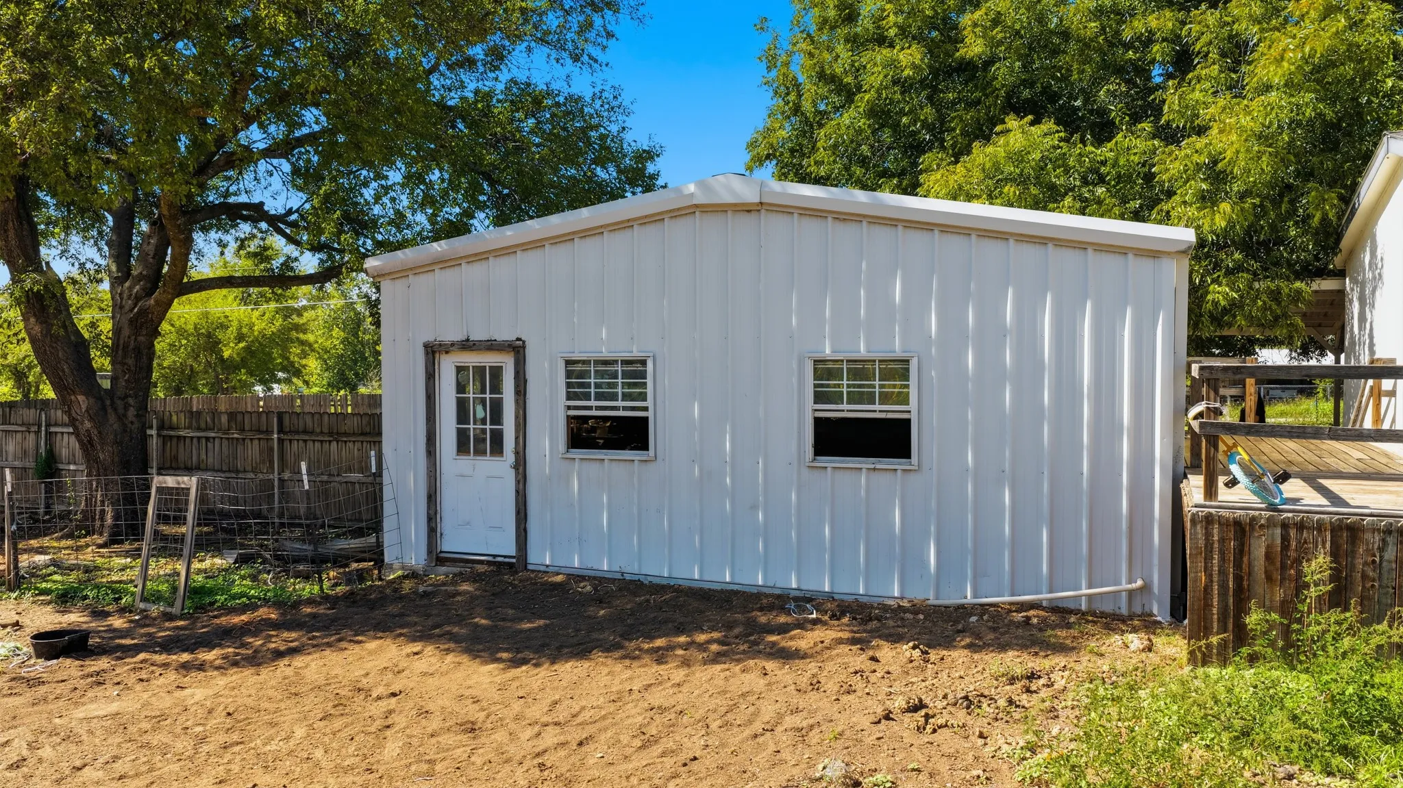 Detached outbuilding featuring vertical metal siding, a single entry door with window pane inserts, and dual double-hung windows