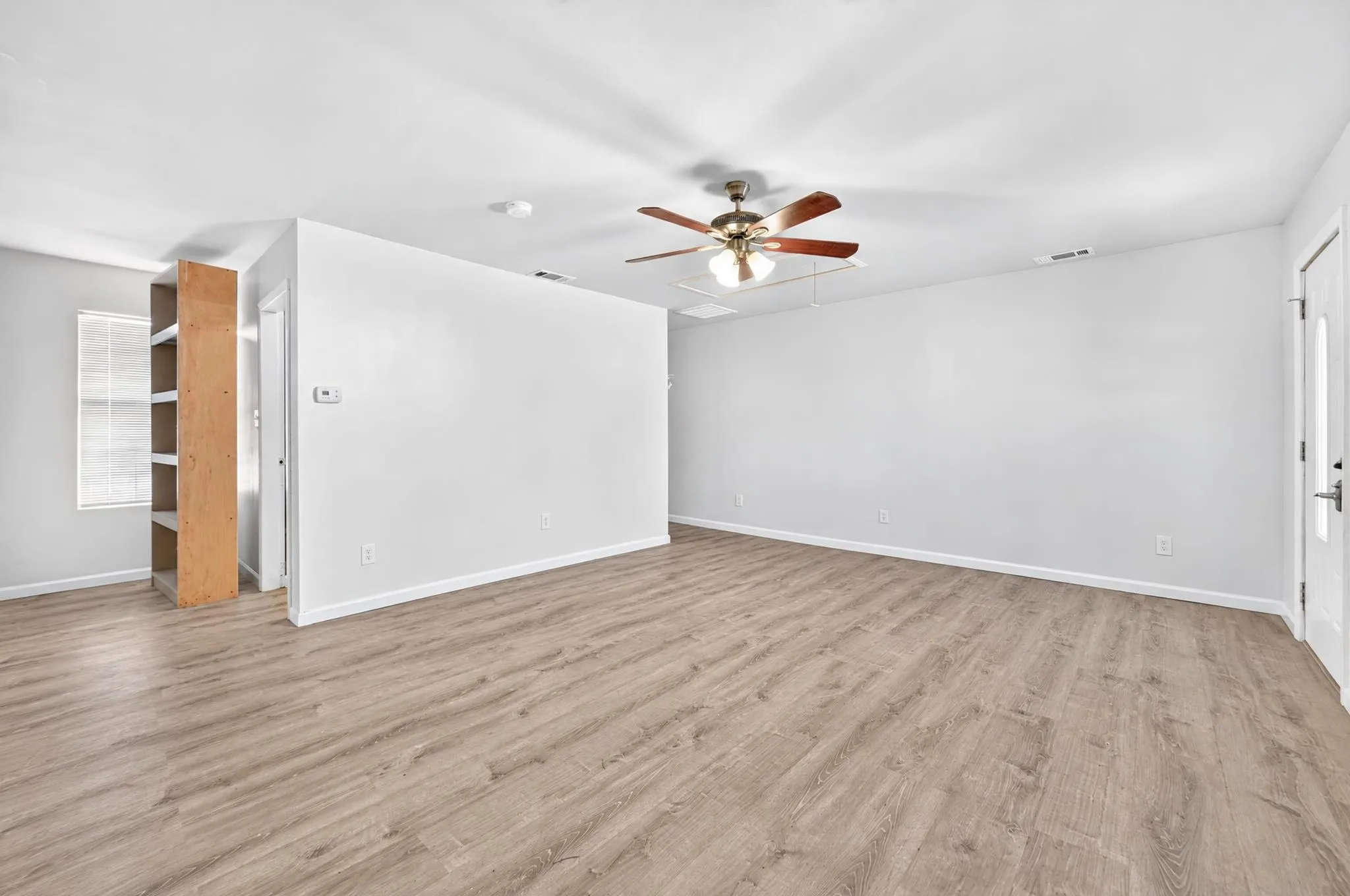 2nd master bedroom Interior space featuring neutral wall paint, wood-finish flooring, a ceiling fan with integrated lighting, and built-in shelving