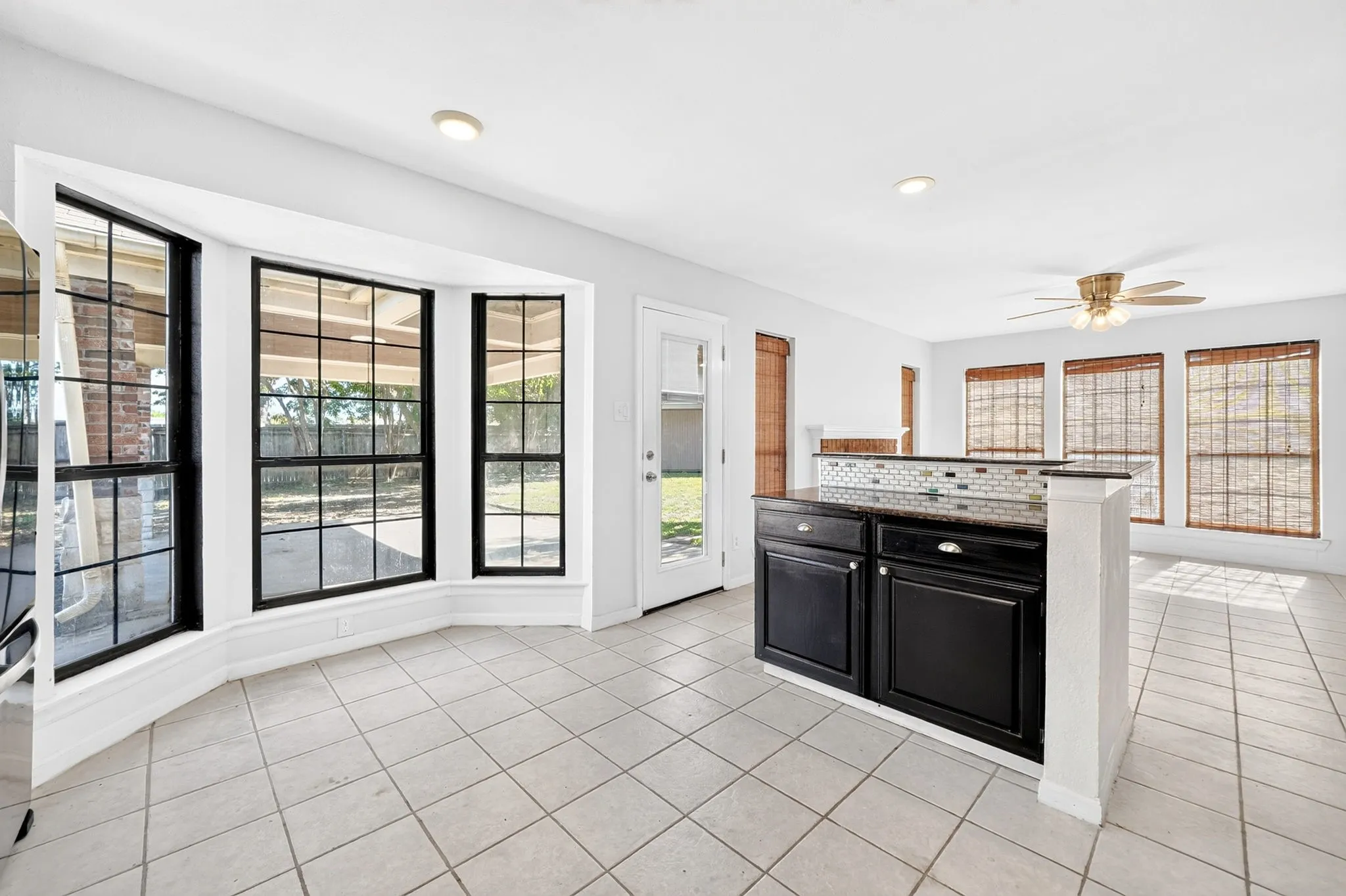 Bay window featuring large-pane grid windows, tile flooring, breakfast bar with dark cabinetry, stone-finish countertop, and recessed ceiling lighting