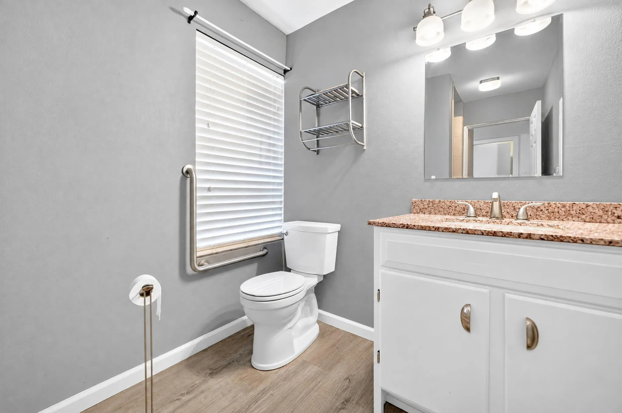 2nd master Bathroom featuring white cabinetry, stone-finish vanity countertop, wood-finish flooring, and a wall-mounted metal shelving unit