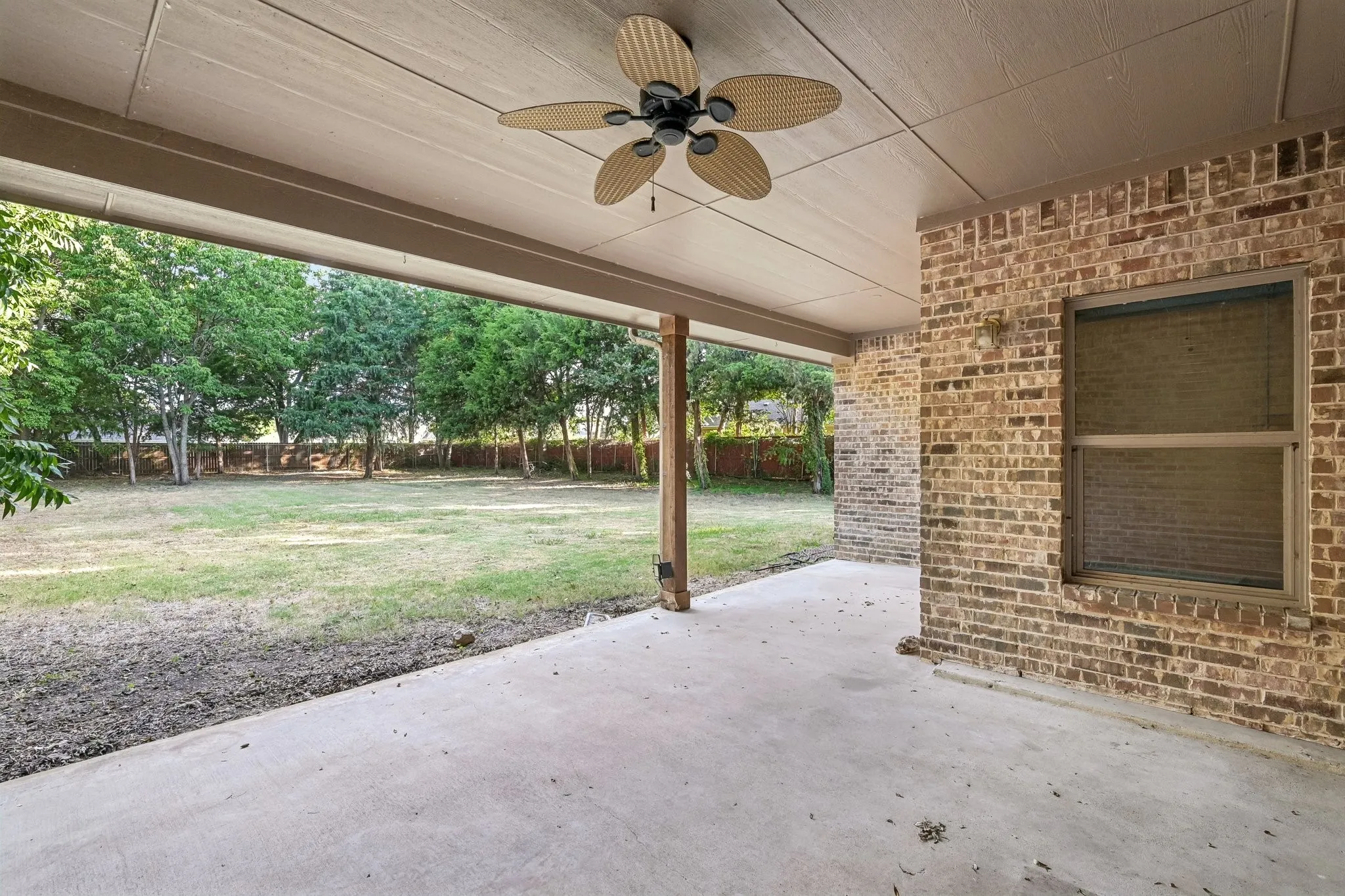 Covered patio with a ceiling fan, brick exterior, and concrete flooring