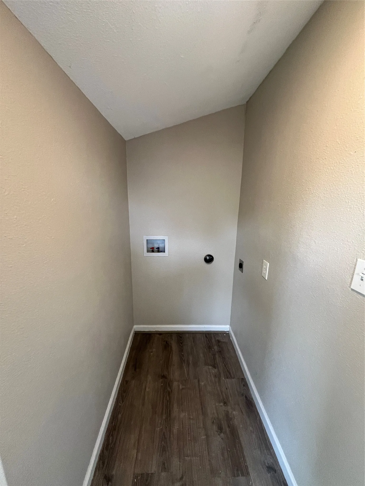 Enclosed alcove featuring wood-finish flooring and integrated utility connections