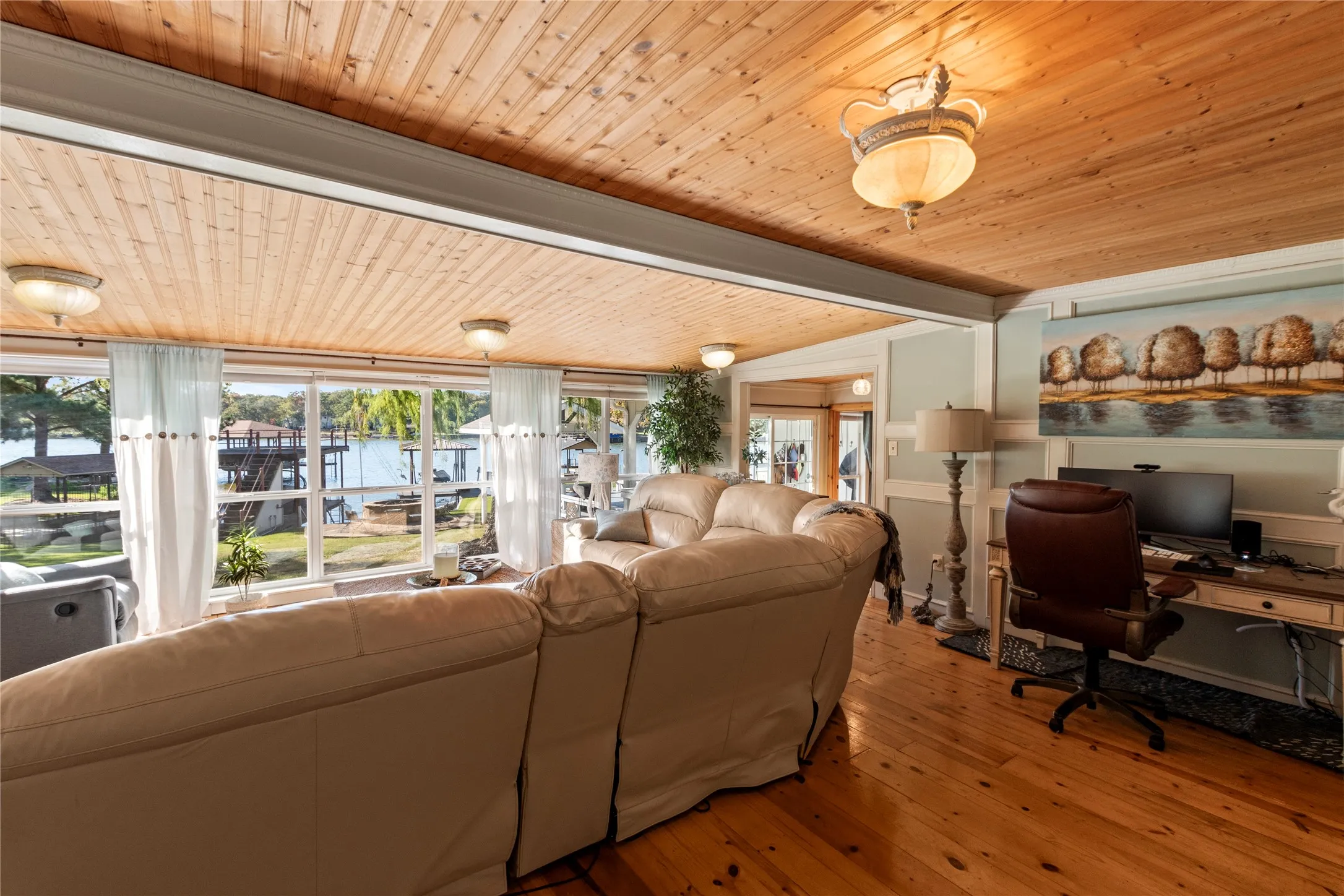 Tongue-and-groove wood-plank ceiling, extensive floor-to-ceiling windows, polished wood-finish flooring, and wall paneling