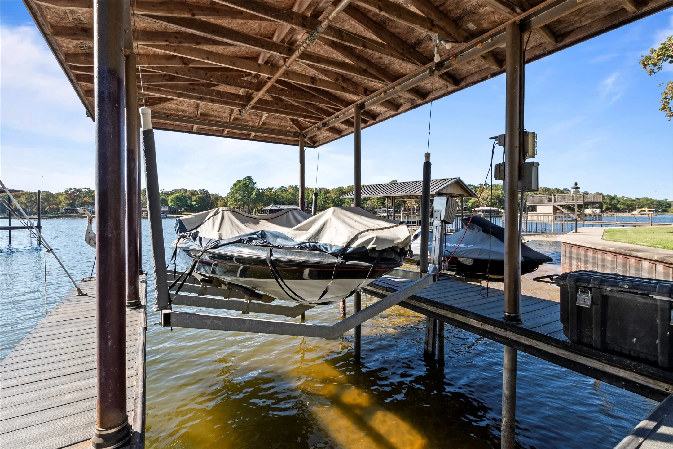 Covered boat slip featuring a heavy-duty mechanical boat lift, composite decking, and metal roofing structure