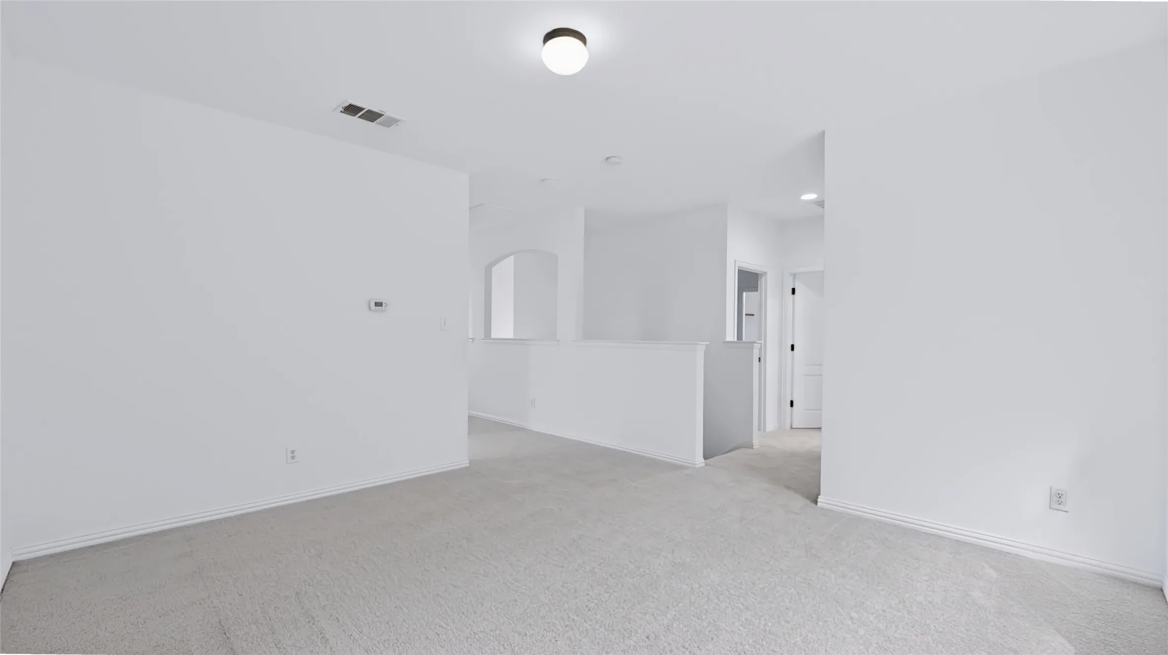 Neutral-toned carpeting, flush-mount ceiling lighting, arched interior architectural detail, and neutral wall palette