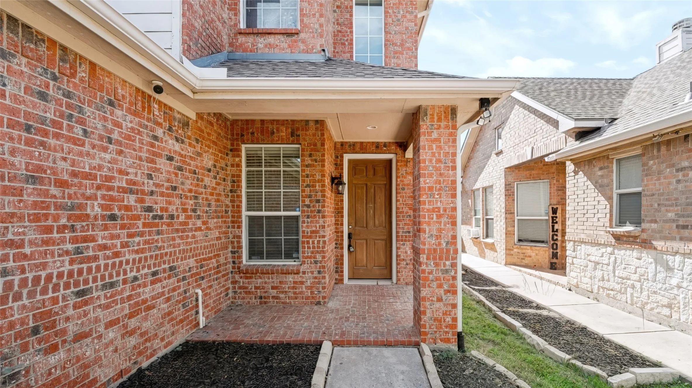 Brick exterior with a covered entryway, multi-paned windows, and a panelled wood entry door