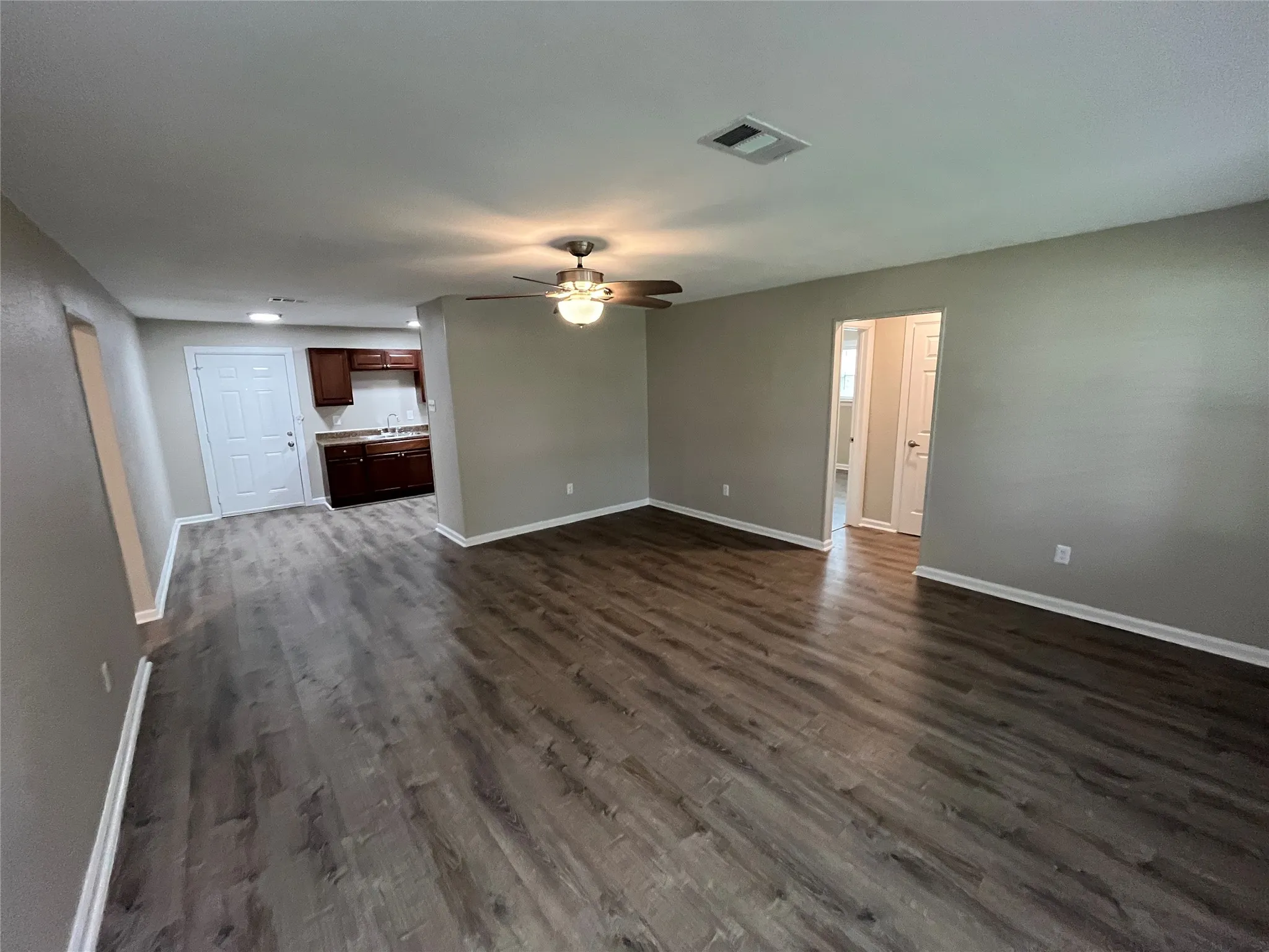 Interior featuring wood-finish flooring, ceiling fan with integrated lighting, and dark-finish cabinetry