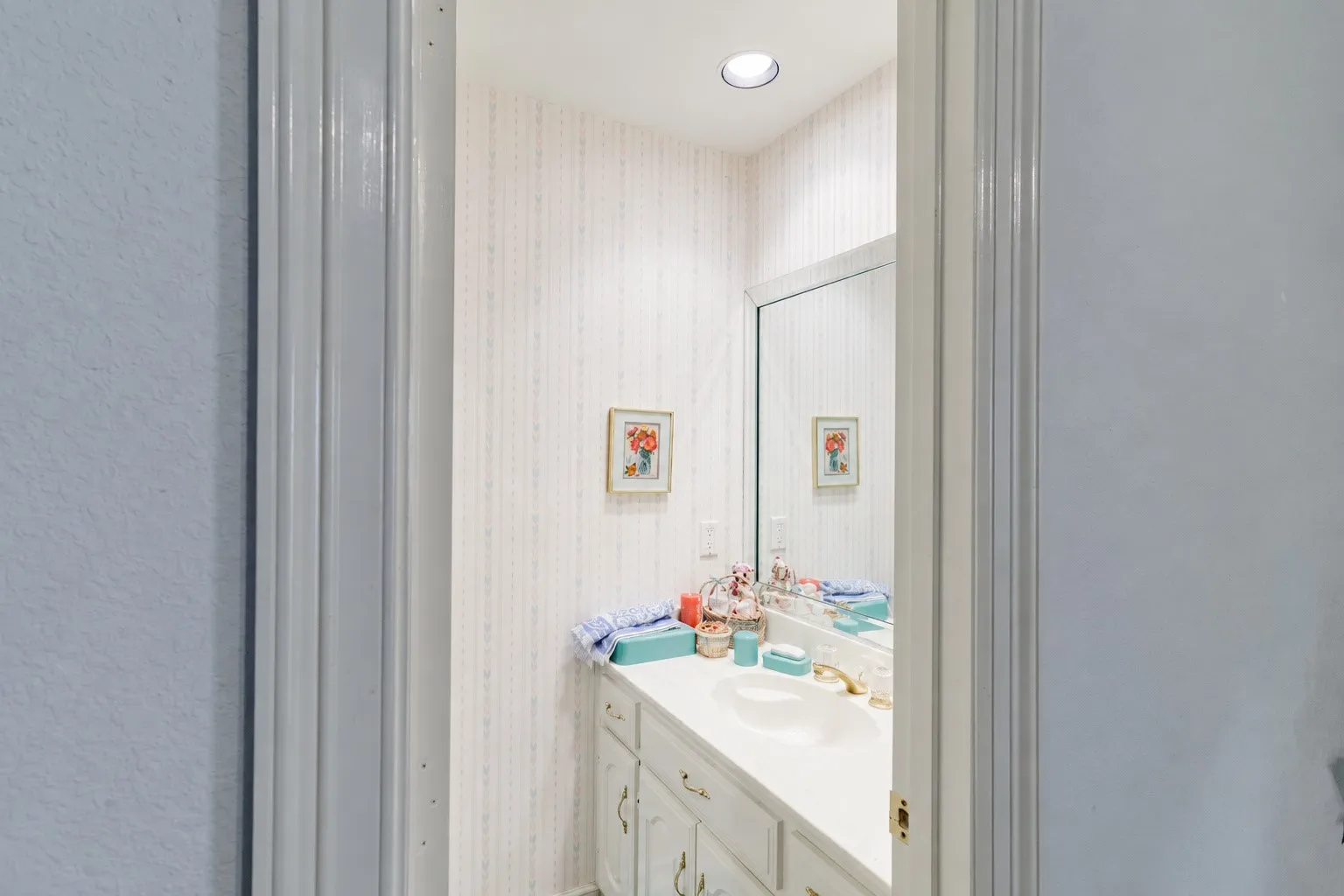 Built-in vanity featuring a seamless countertop with an integrated basin, white cabinetry, a large wall-mounted mirror, and recessed ceiling lighting