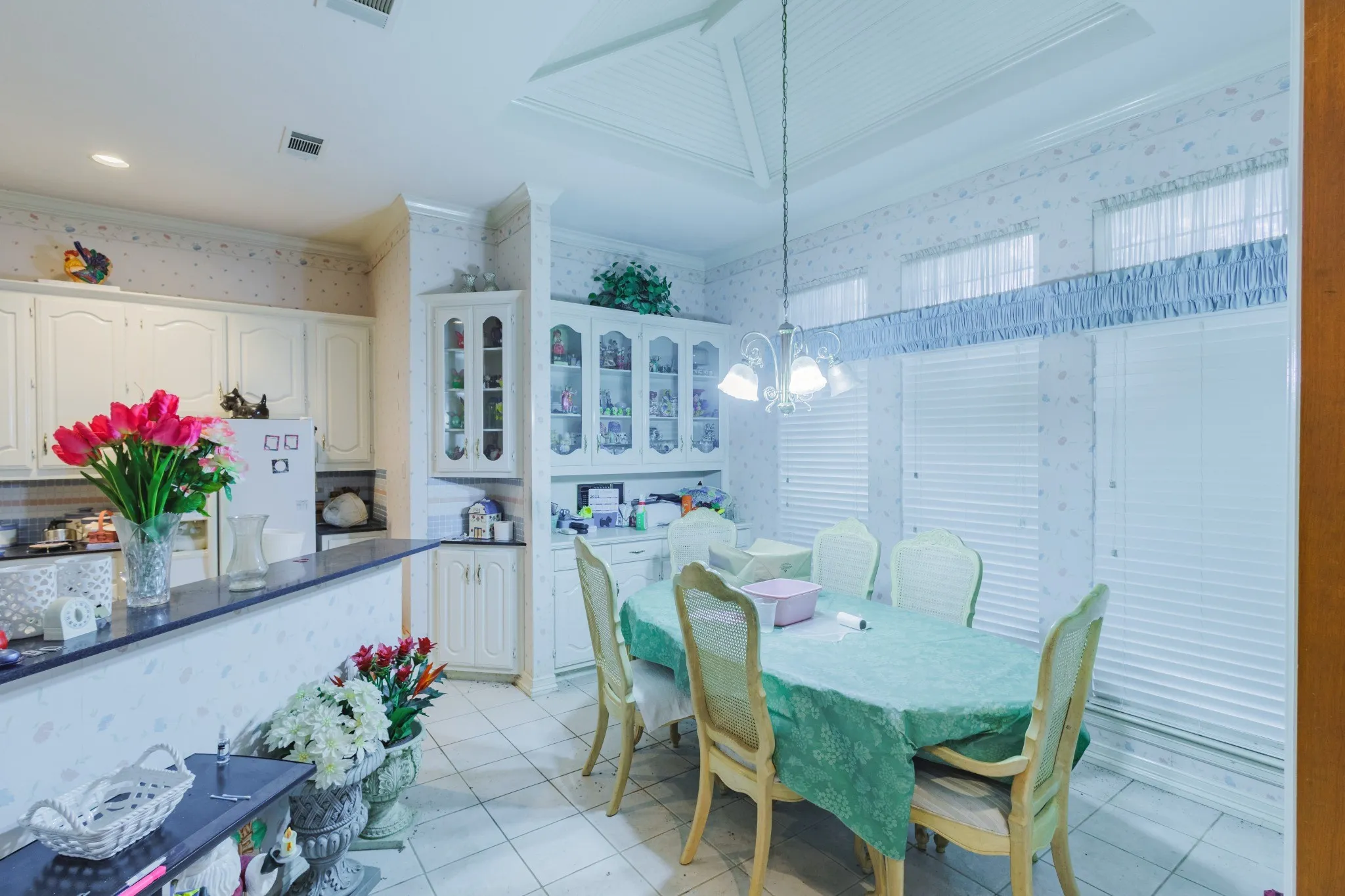 Kitchen featuring white cabinetry, built-in display hutch, stone-finish countertops, tile flooring, and a tray ceiling