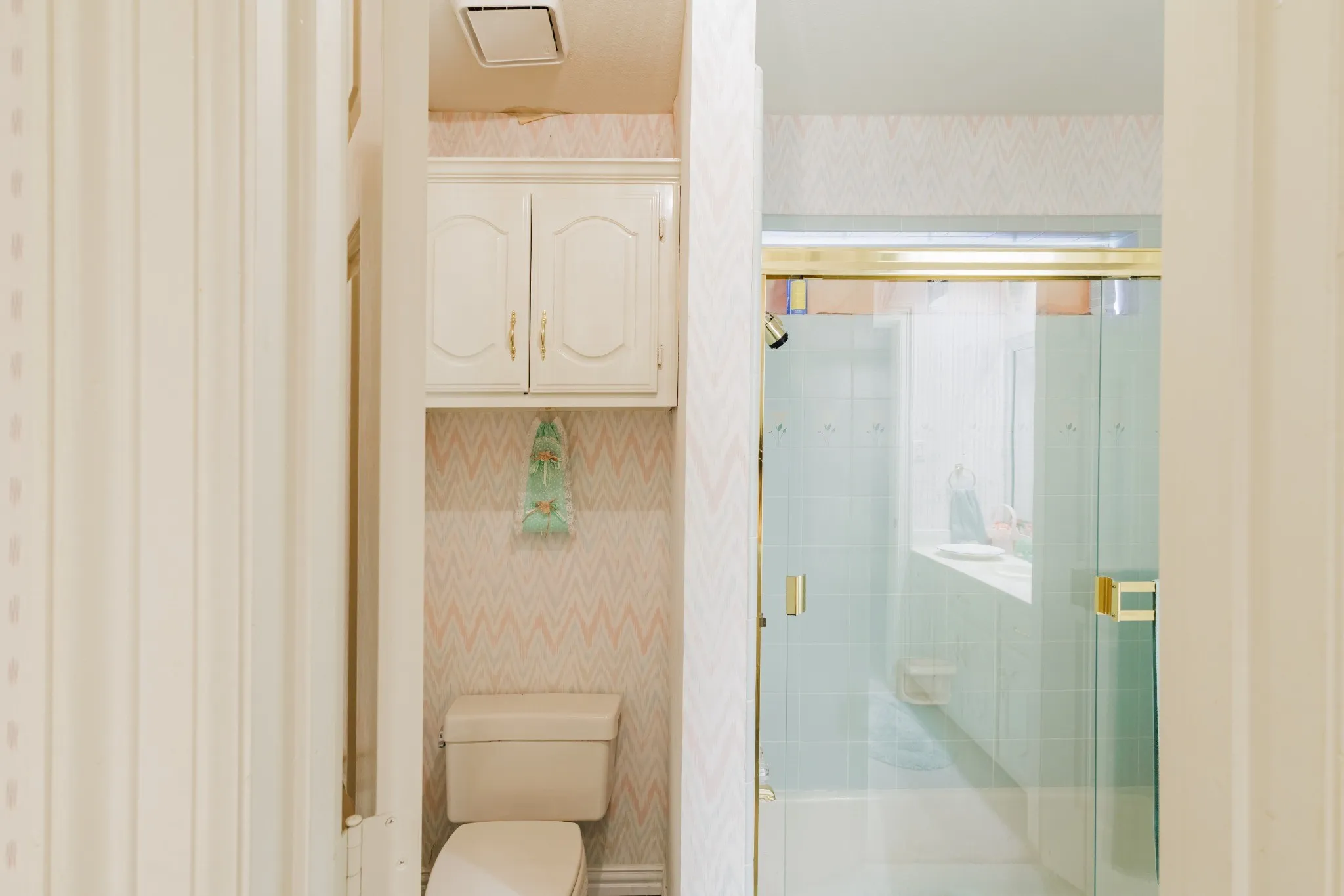 Bathroom featuring an enclosed shower with glass sliding doors, wall-mounted cabinetry, and a dual-flush toilet