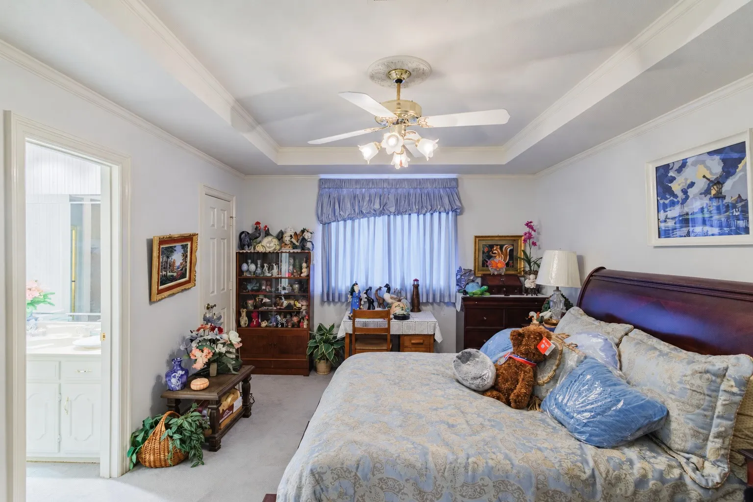 Tray ceiling with a central multi-light ceiling fan and crown molding