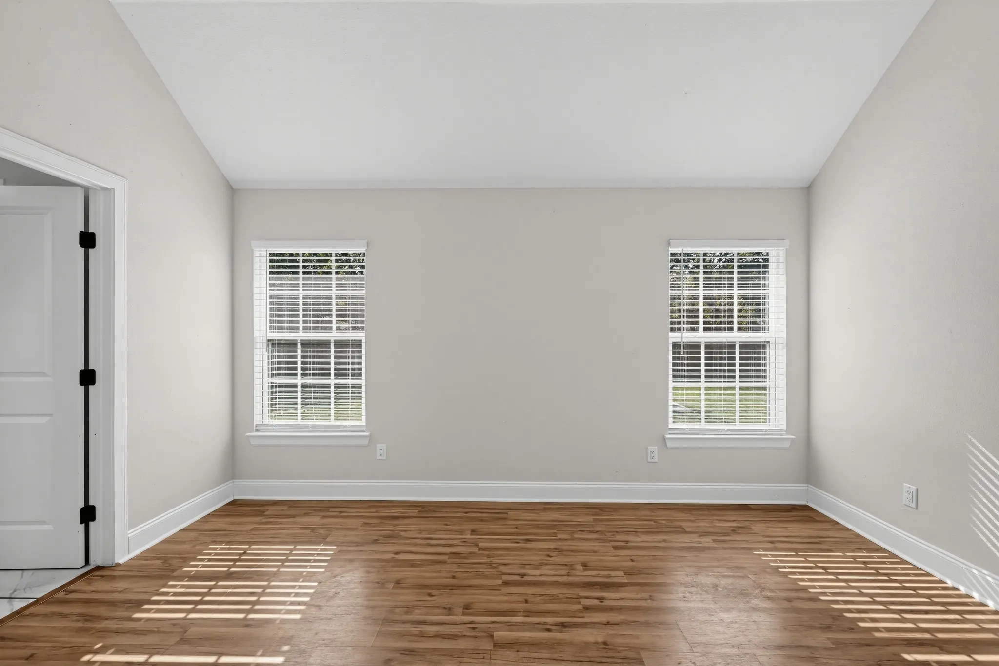 Vaulted ceilings, wood-finish flooring, and dual windows with integrated blinds