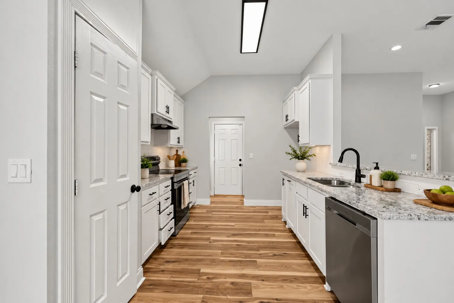 Kitchen featuring white shaker-style cabinetry, stone-finish countertops, wood-finish flooring, a stainless steel dishwasher, and a matte black gooseneck faucet