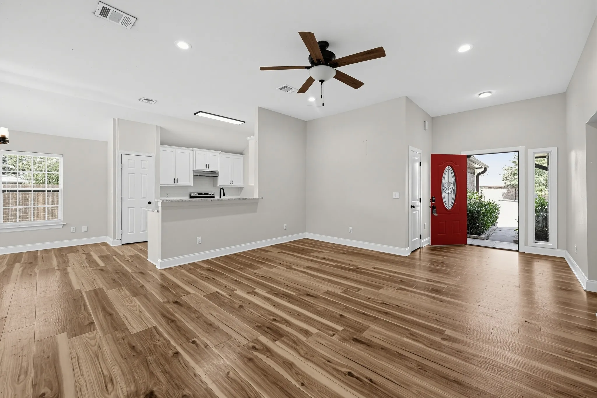 Living area featuring wood-finish flooring, recessed lighting, a ceiling fan, white cabinetry, and a peninsula counter