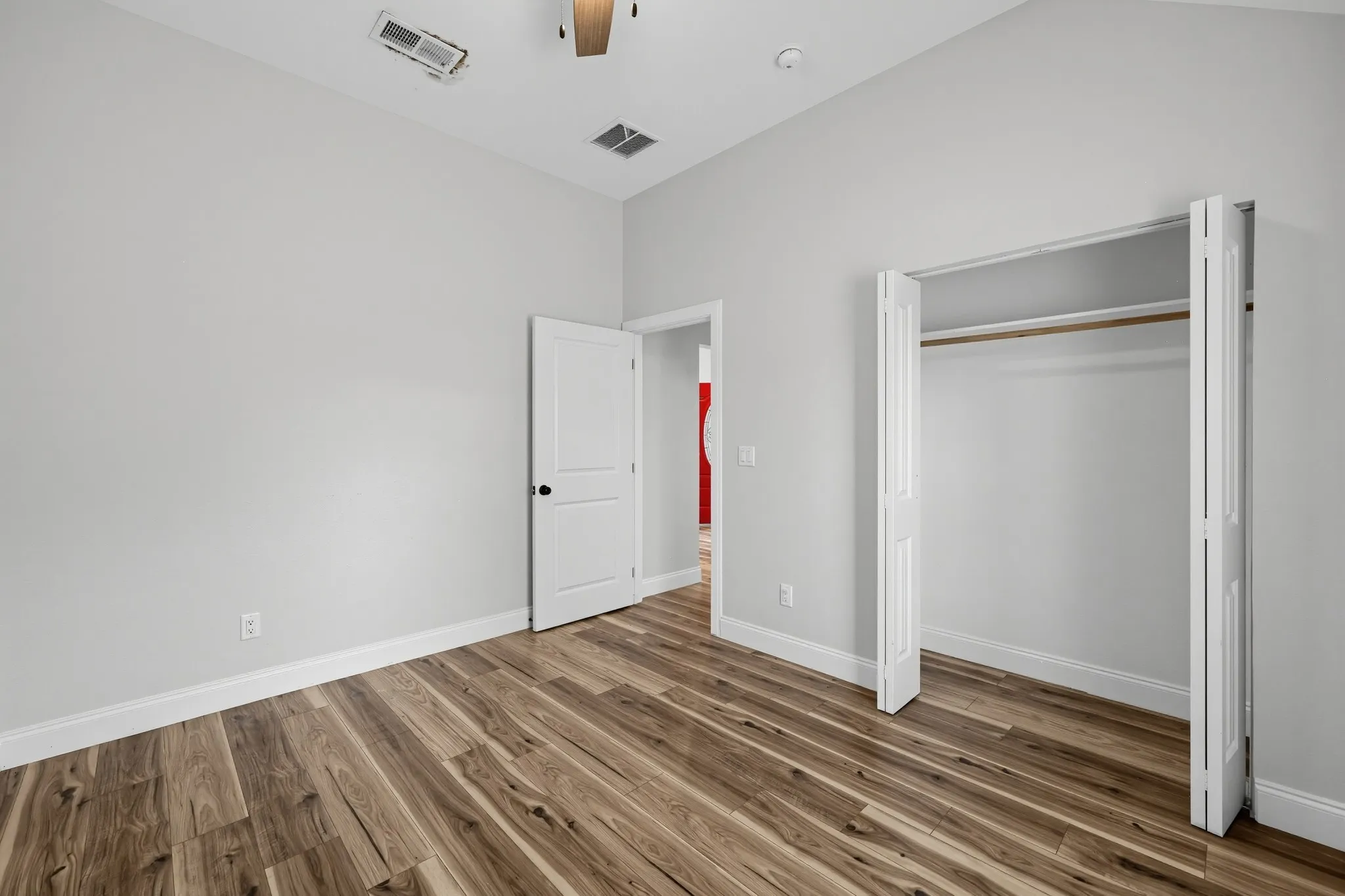 Vaulted ceiling, wood-finish flooring, and built-in closet featuring bi-fold doors