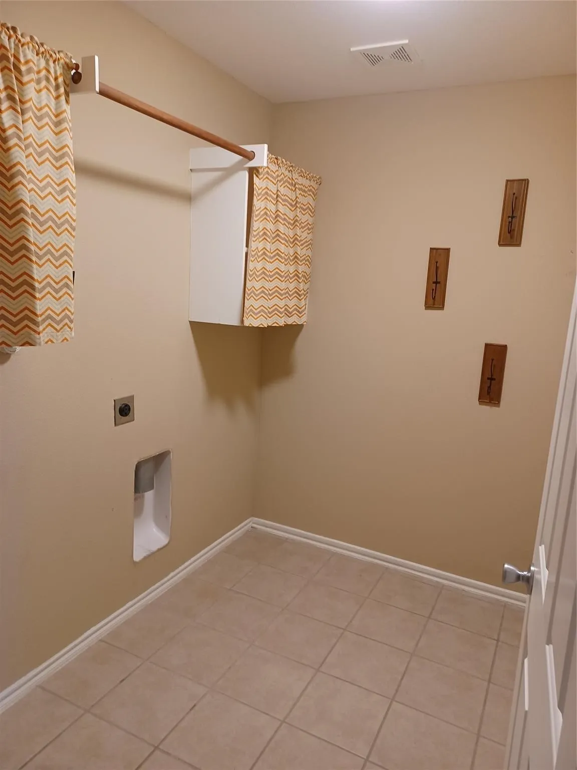 Tile flooring, wall-mounted cabinetry, and a ceiling-mounted light fixture