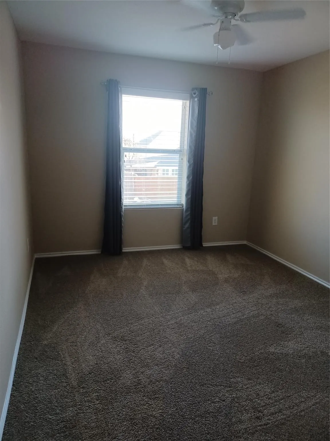 Carpeted room with a ceiling fan, a window with blinds, and neutral tone walls
