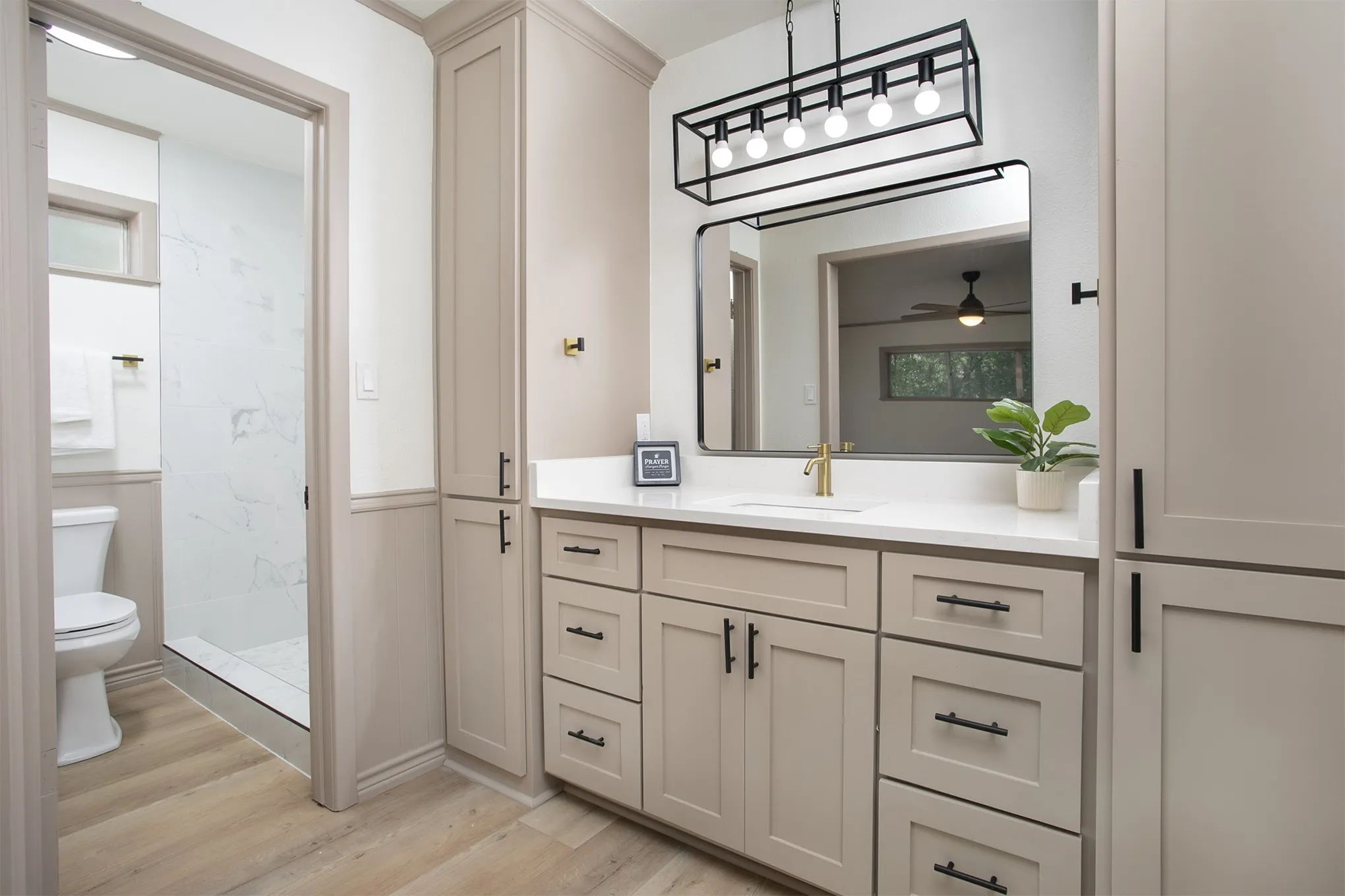Custom vanity featuring soft-toned cabinetry, a quartz countertop, matte black hardware, a rectangular undermount sink, and a multi-bulb geometric light fixture