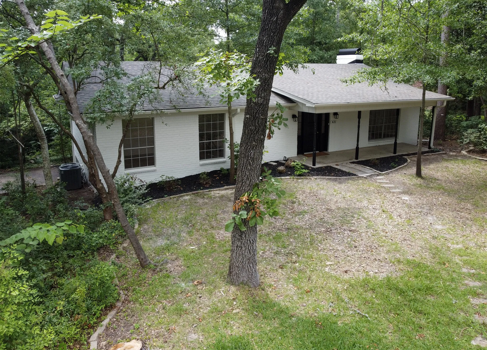 Single-story exterior featuring a white painted brick facade, covered front porch, asphalt shingle roof, chimney, and multi-pane windows