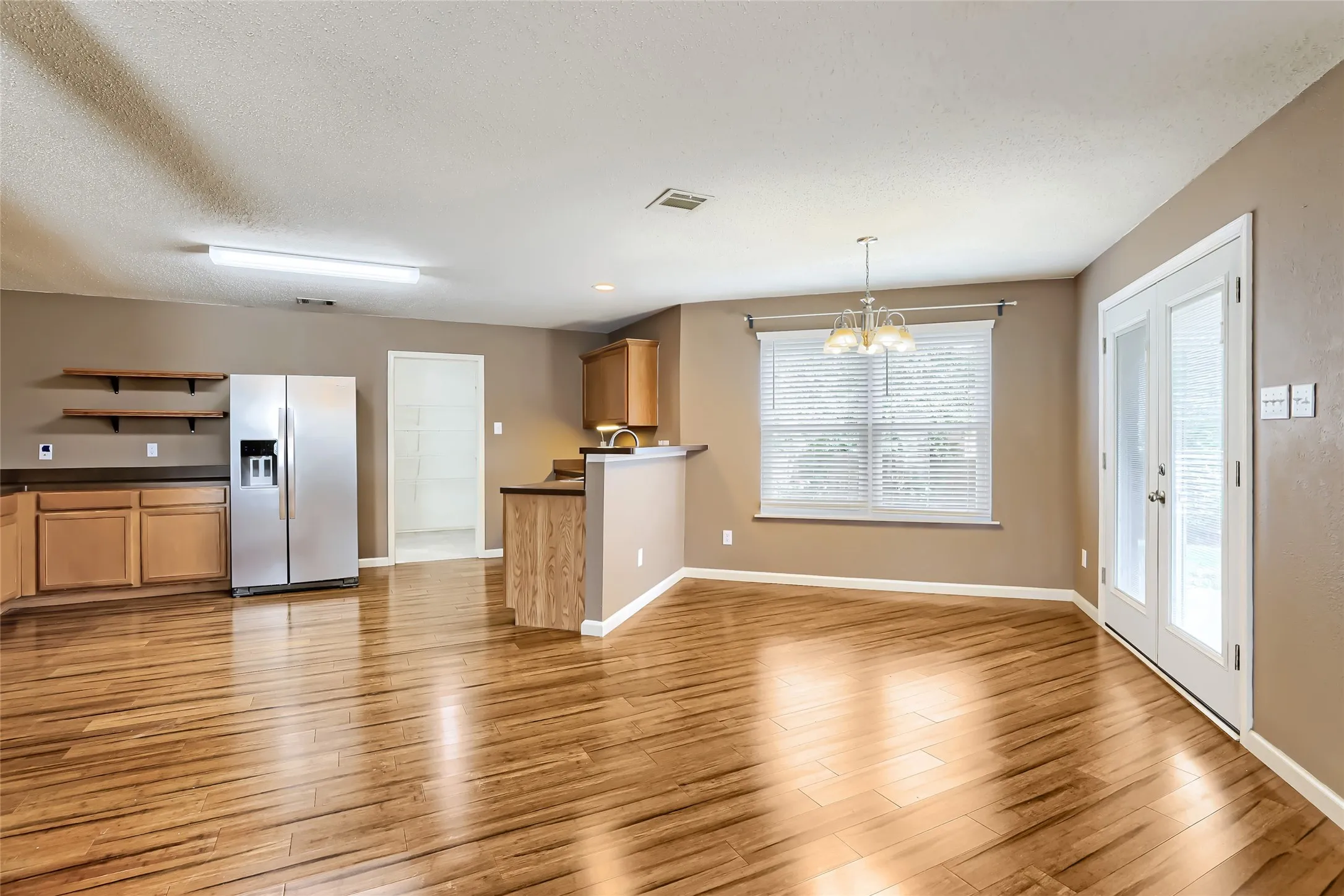 Wood-finish flooring, shaker-style wood cabinetry, stainless steel refrigerator, multi-pane glass french doors, and built-in shelving