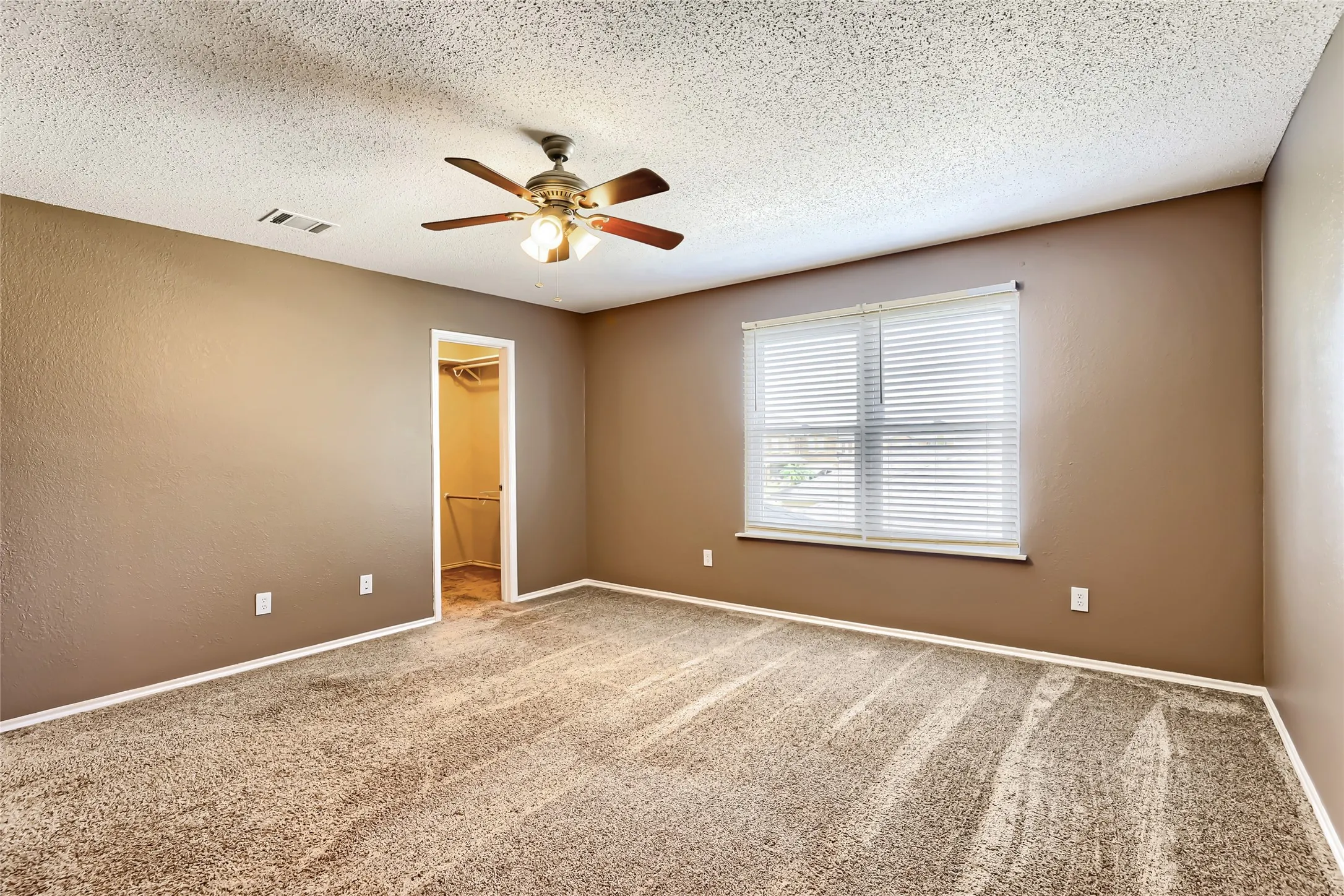 Room featuring neutral-toned walls, carpeting, a ceiling fan with integrated lighting, and an enclosed closet with built-in shelving