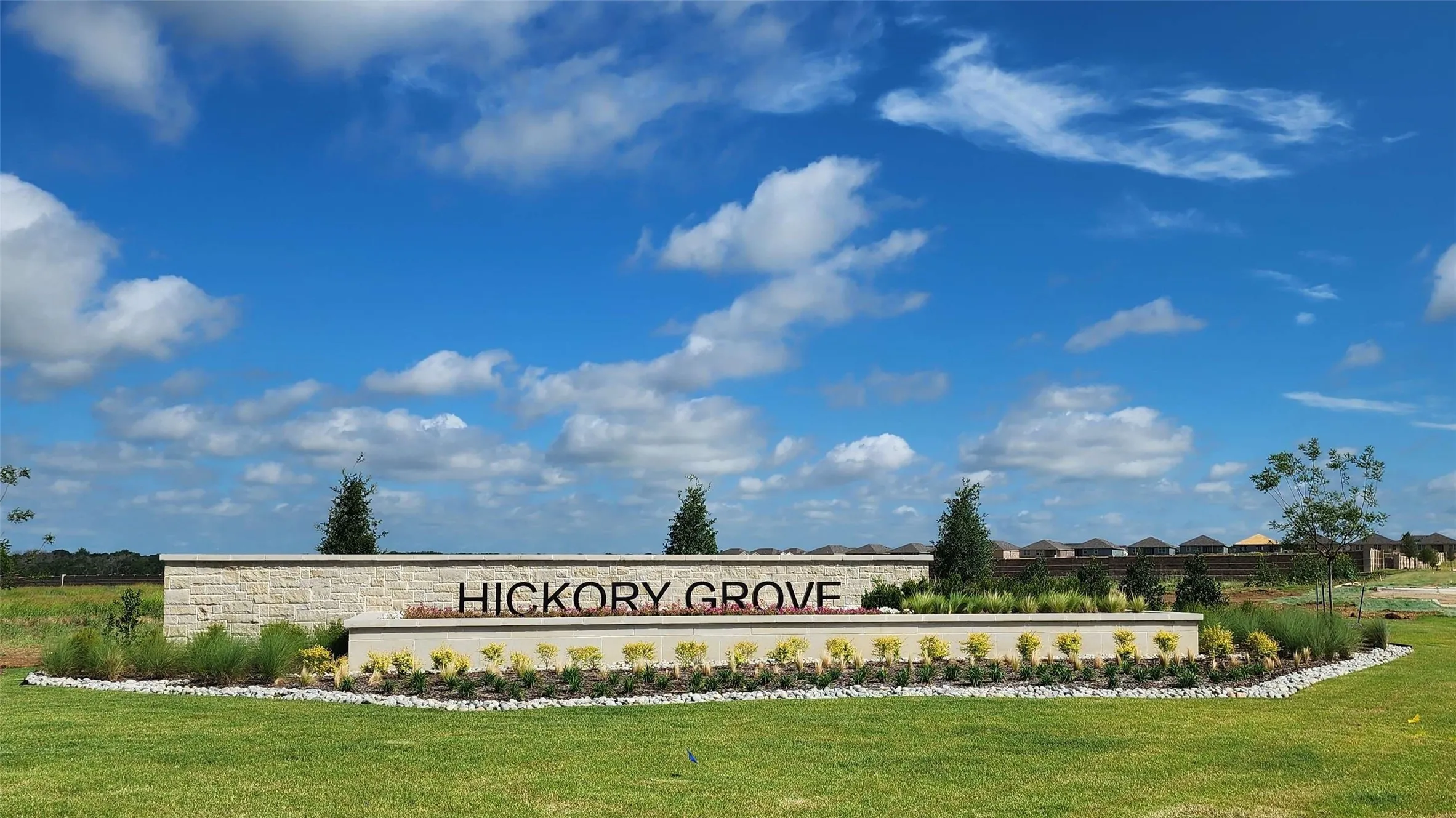 Hickory Grove monument sign featuring stone masonry construction, tiered hardscaping, and manicured landscaping
