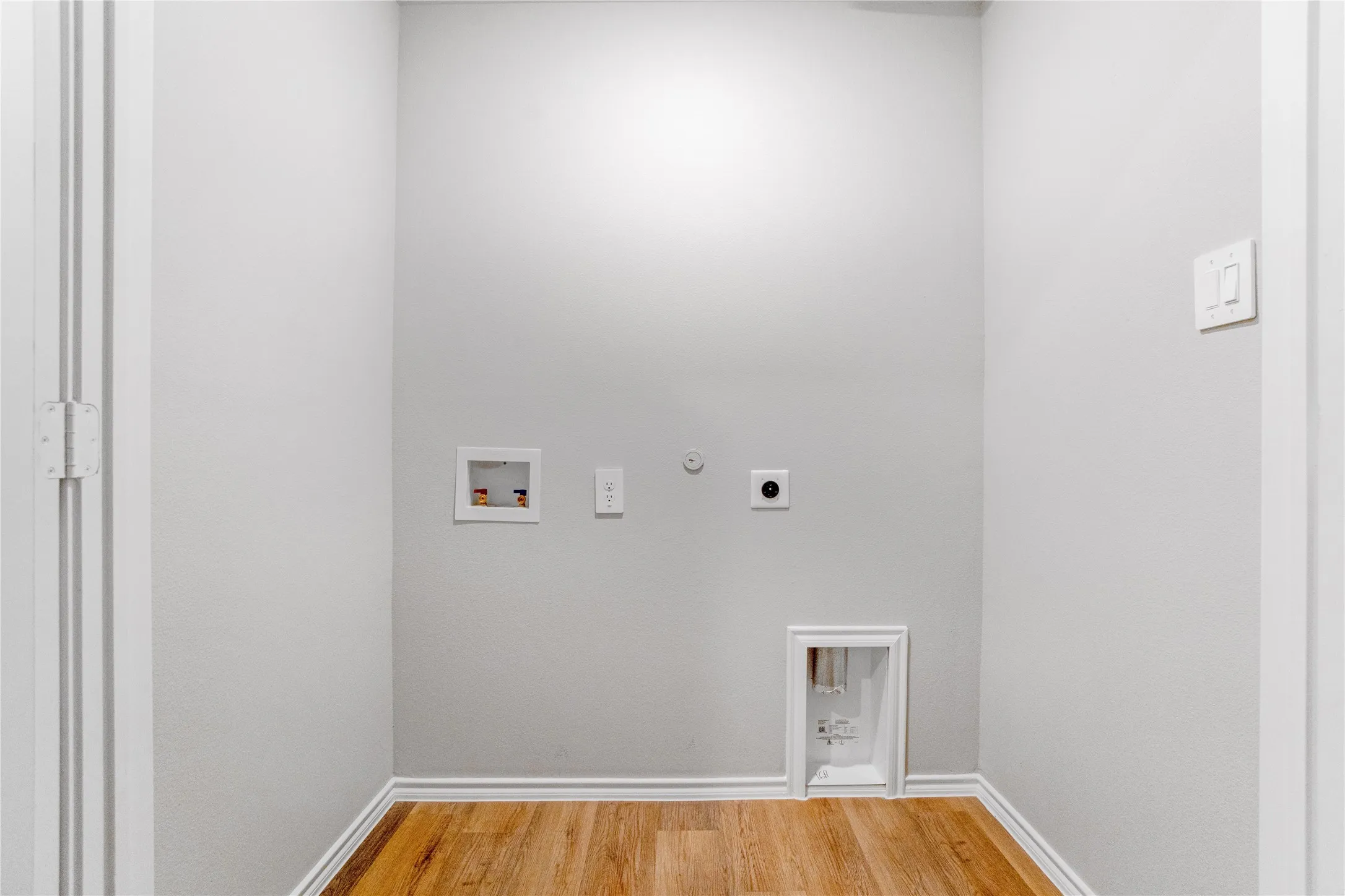 Dedicated utility alcove featuring wood-finish flooring and integrated washer and dryer hookups