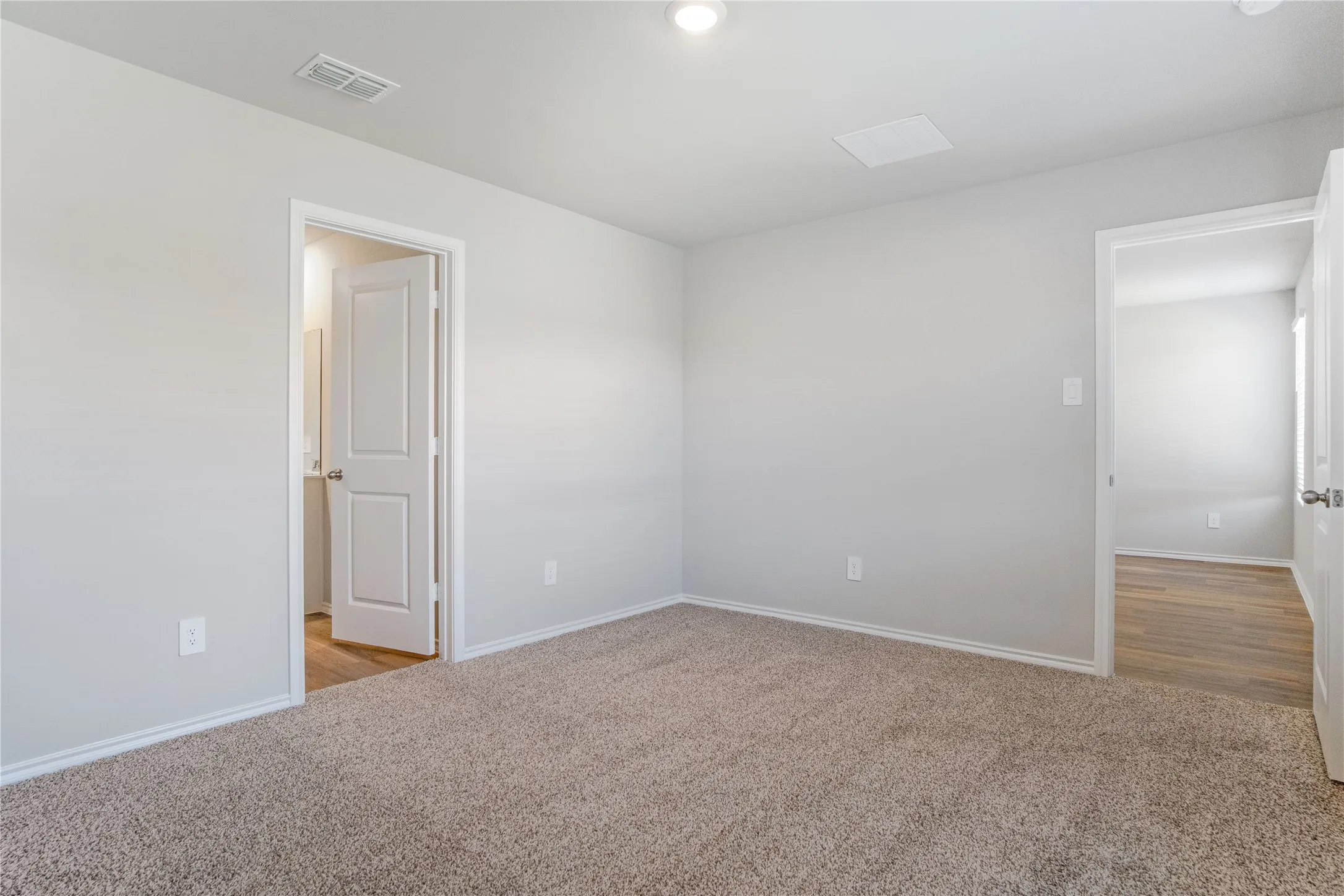 Neutral wall tones, wall-to-wall carpeting, and recessed lighting fixtures