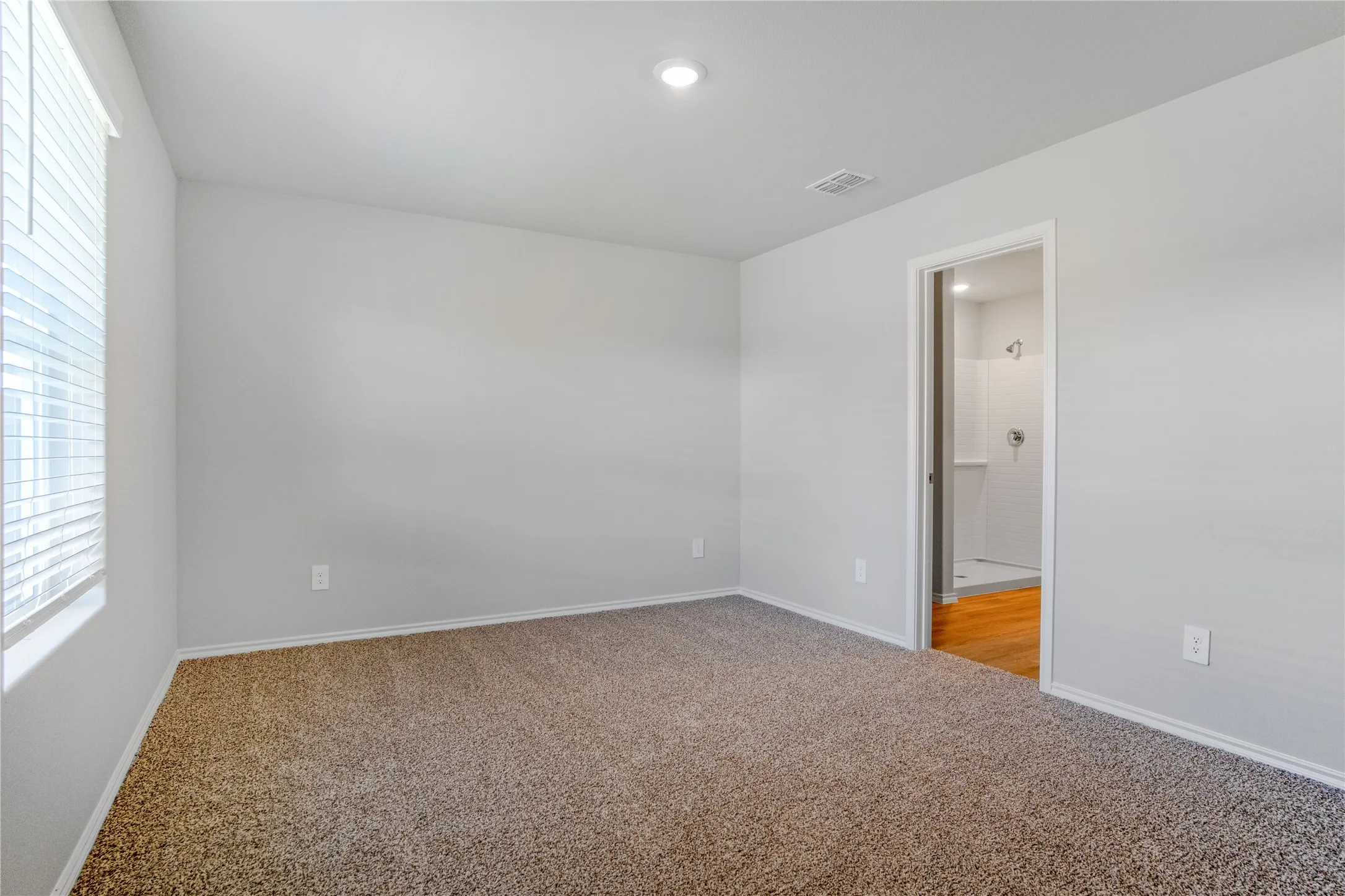 Neutral-toned interior space featuring wall-to-wall carpeting, recessed lighting, and horizontal window blinds