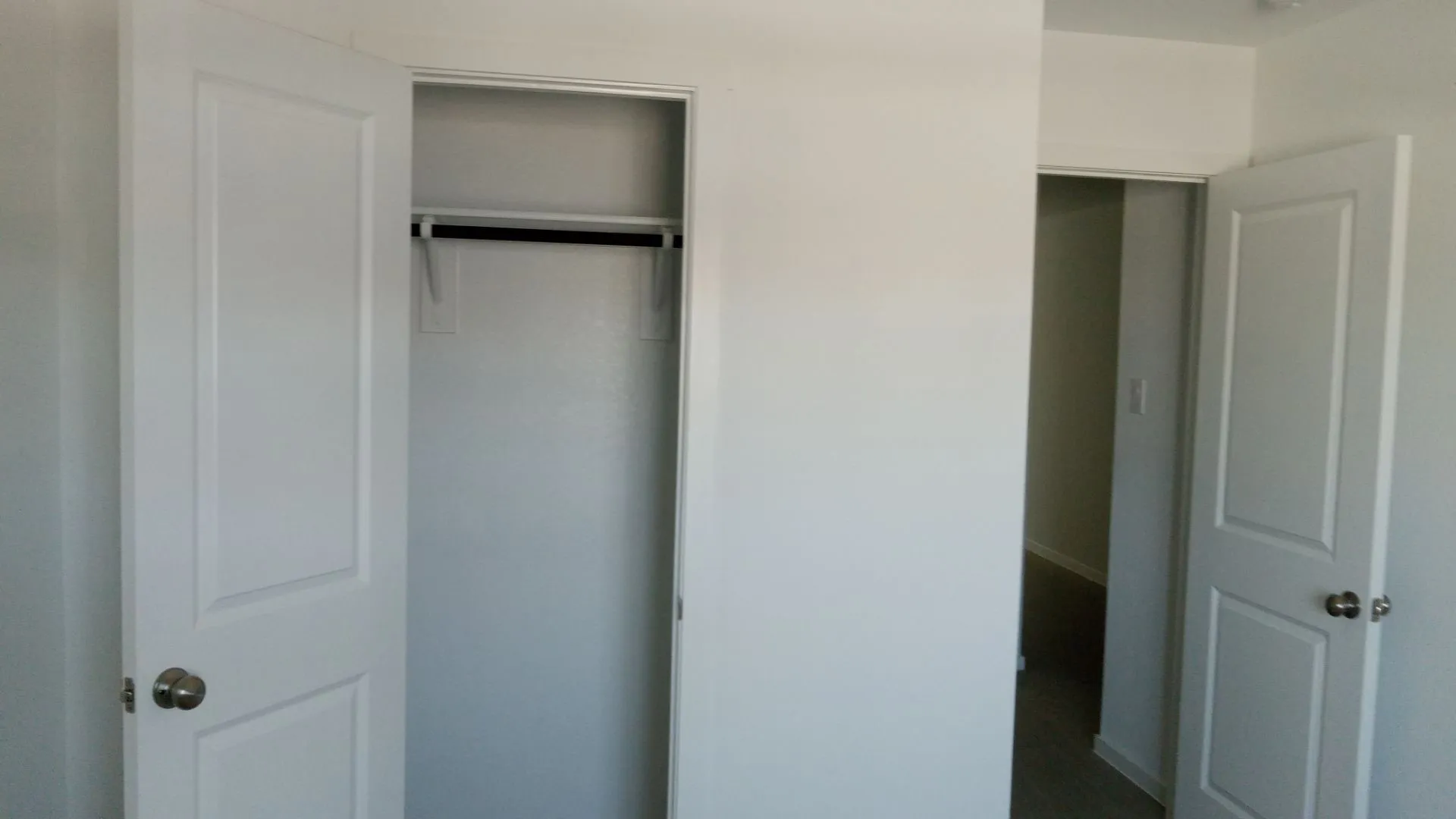 Interior closet featuring a built-in shelf and hanging rod, complemented by two-panel interior doors with brushed nickel hardware