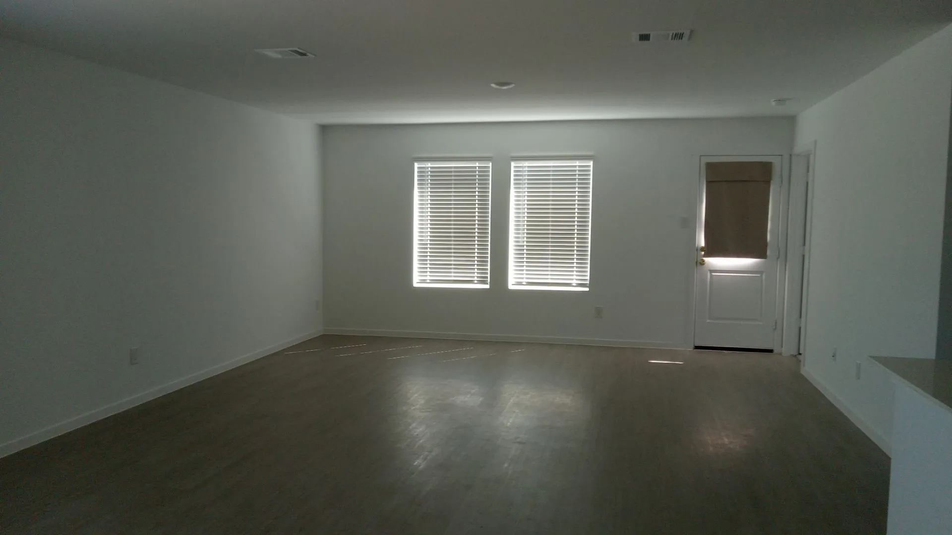 Interior room featuring wood-finish flooring, recessed ceiling lighting, and two windows with horizontal blinds