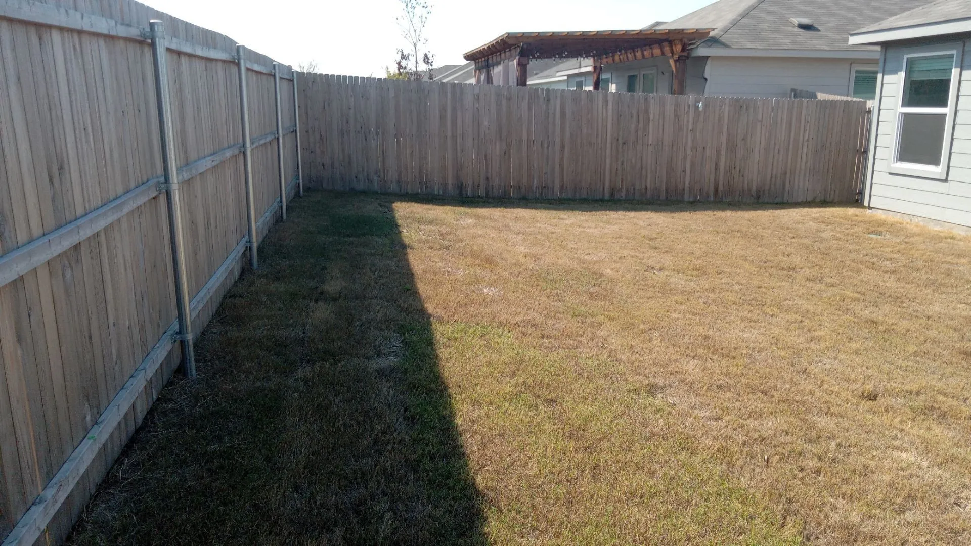 Backyard area featuring a wood privacy fence and a pergola