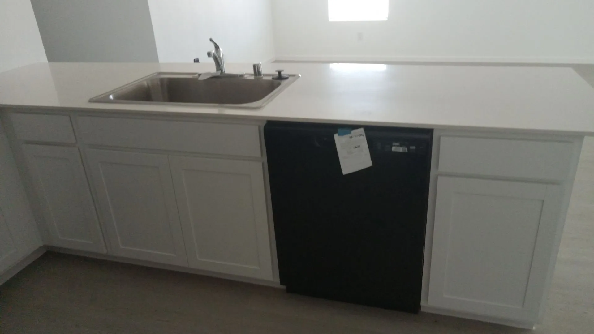 Kitchen island featuring white Shaker-style cabinetry, solid-surface countertops, an undermount stainless steel sink with a high-arch faucet, and an integrated dishwasher