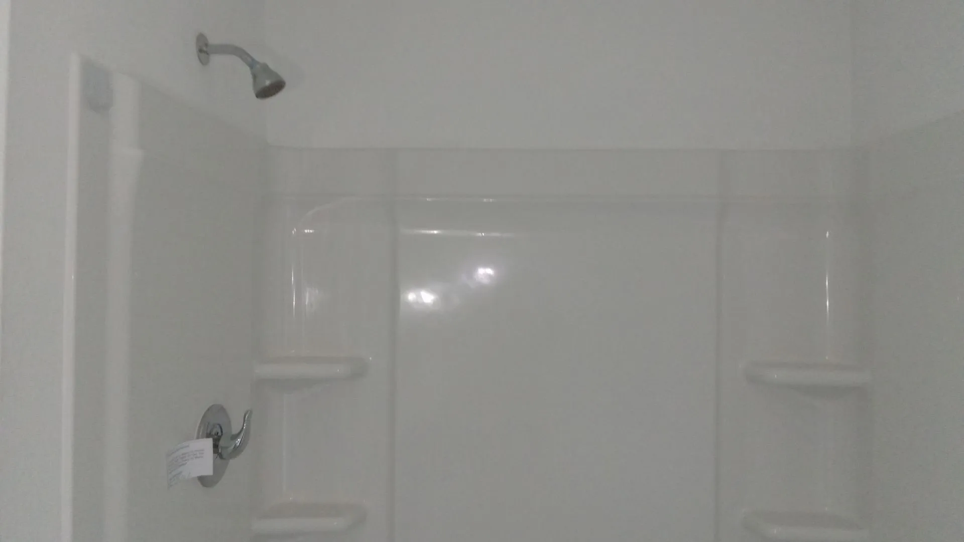 Shower enclosure featuring a high-gloss composite surround with integrated shelving and a chrome single-handle mixing valve