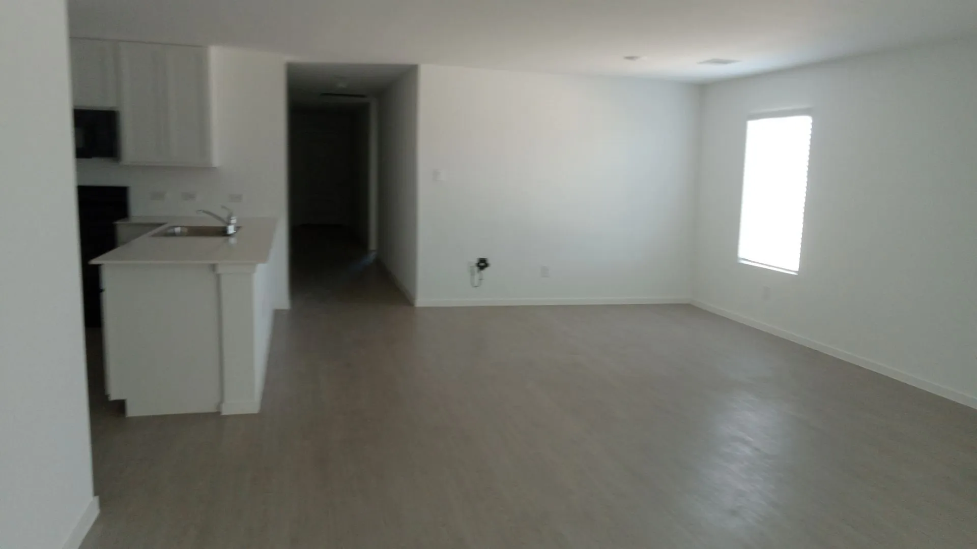 Open-concept interior featuring wood-finish flooring, white cabinetry, solid-surface countertops, and recessed lighting