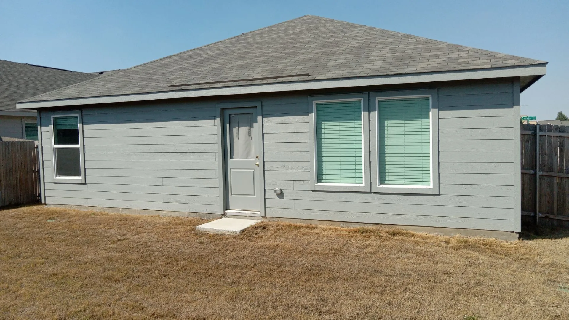 Exterior facade featuring horizontal lap siding, a hip roof with composition shingles, and a rear door entry