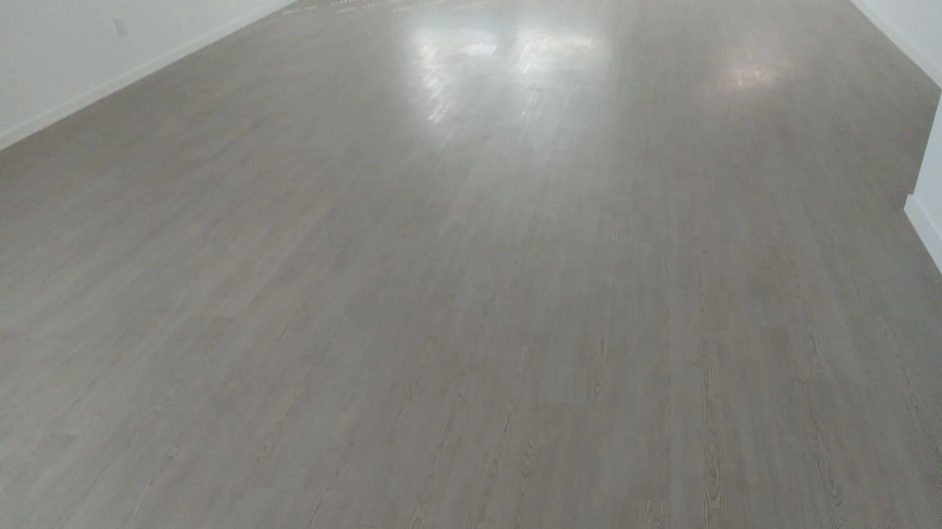 Neutral-toned wood-finish flooring with uniform plank installation and white wall finish
