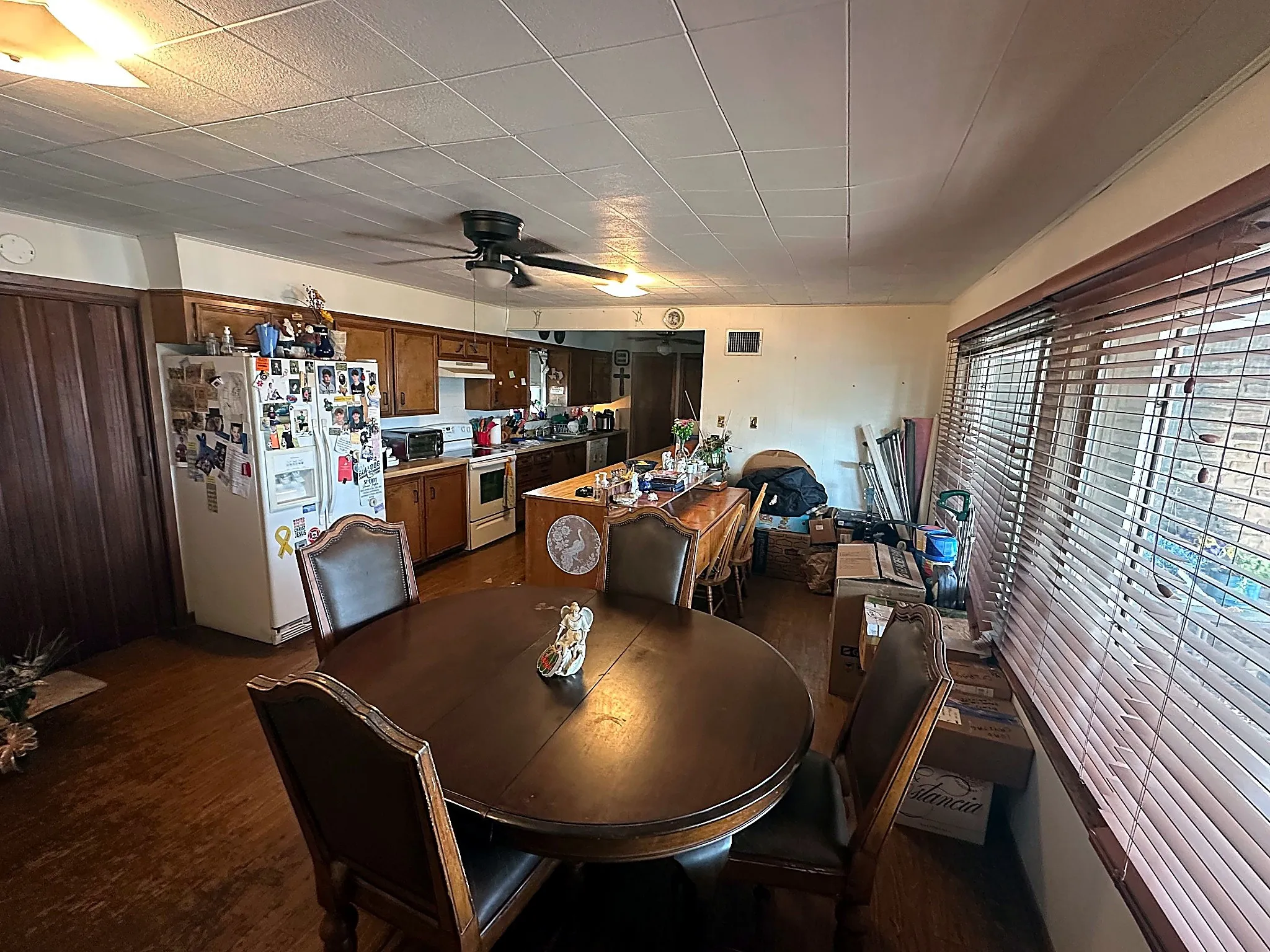 Kitchen featuring wood cabinetry, a breakfast bar, wood-finish flooring, and horizontal window blinds