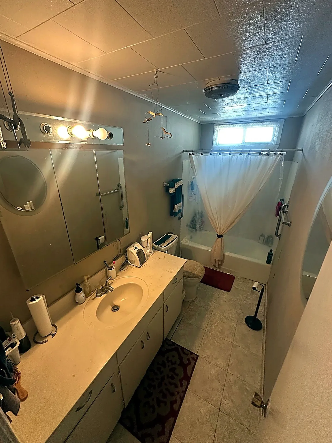 Full-width vanity featuring a molded sink, expansive countertop, integrated medicine cabinet with mirrored doors, and tile flooring