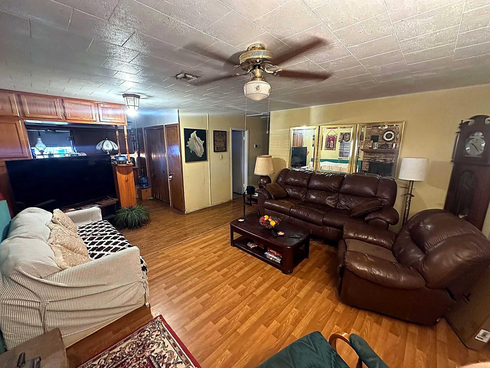 Wood-finish flooring, ceiling fan with integrated lighting, mirrored wall accents, and built-in wood cabinetry