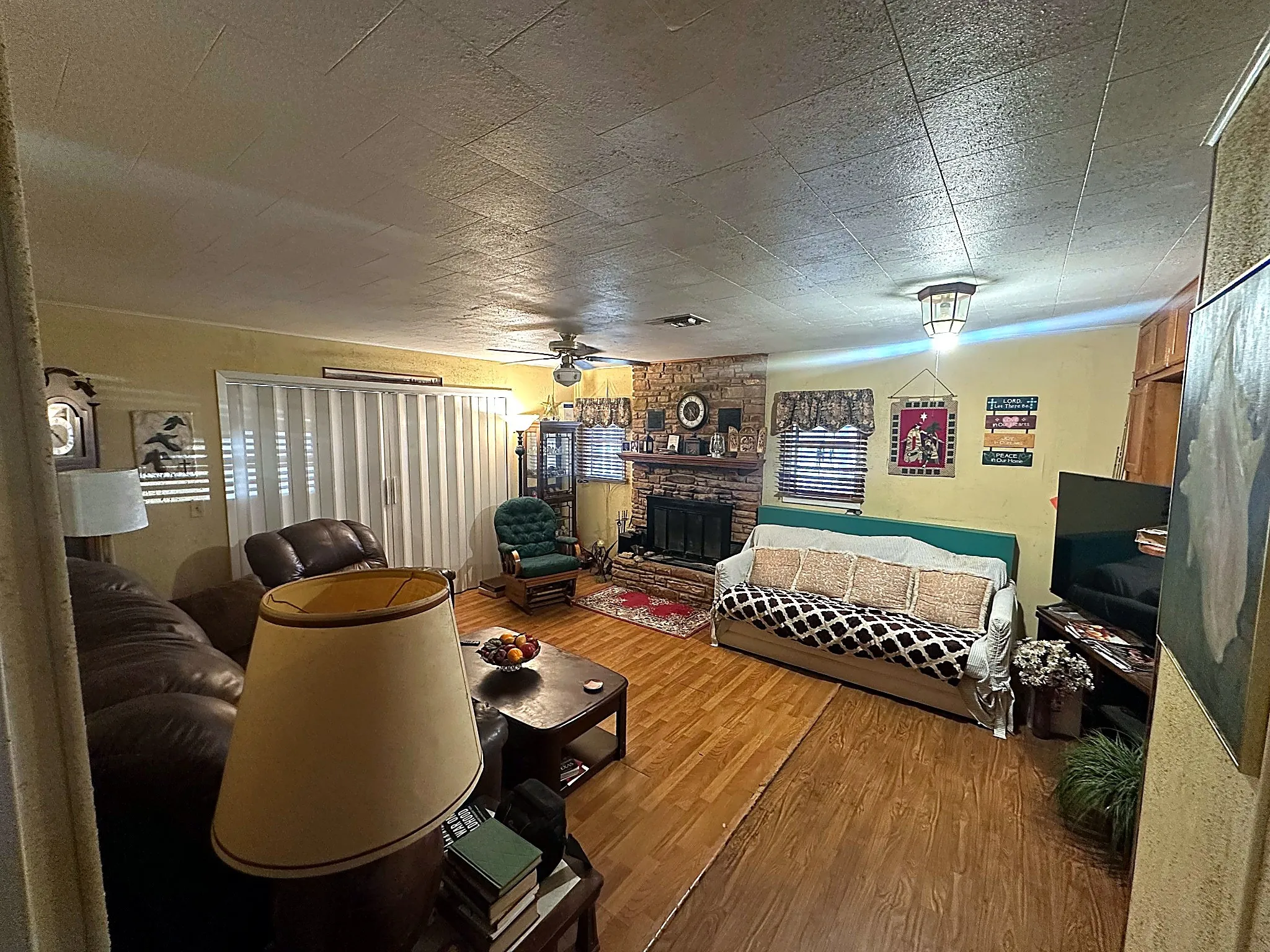 Living area featuring wood-finish flooring, a floor-to-ceiling brick masonry fireplace with a wood mantel, and a ceiling fan