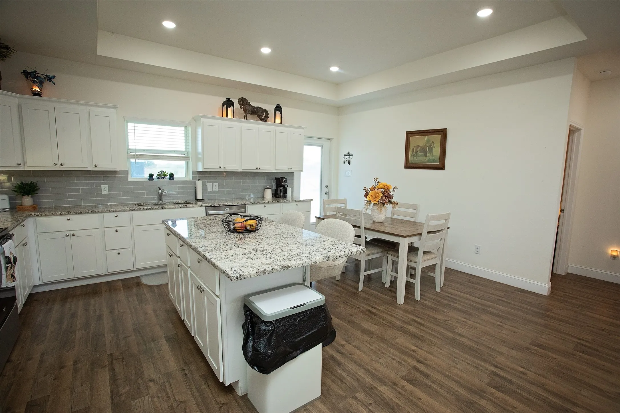 Kitchen featuring white cabinetry, stone countertops, central island, wood-finish flooring, and recessed ceiling lighting