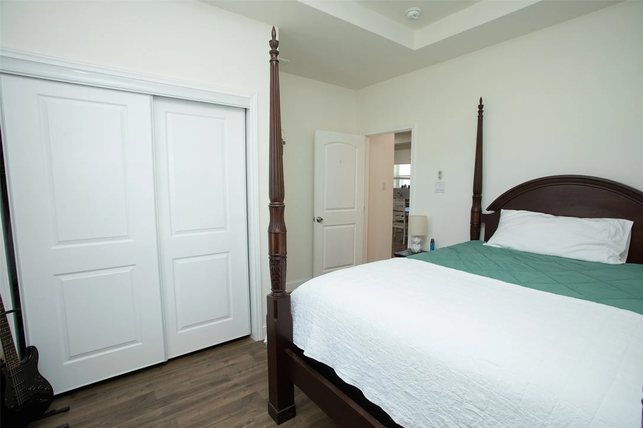 Wood-finish flooring, tray ceiling, and sliding-panel closet doors with two-panel architectural detailing
